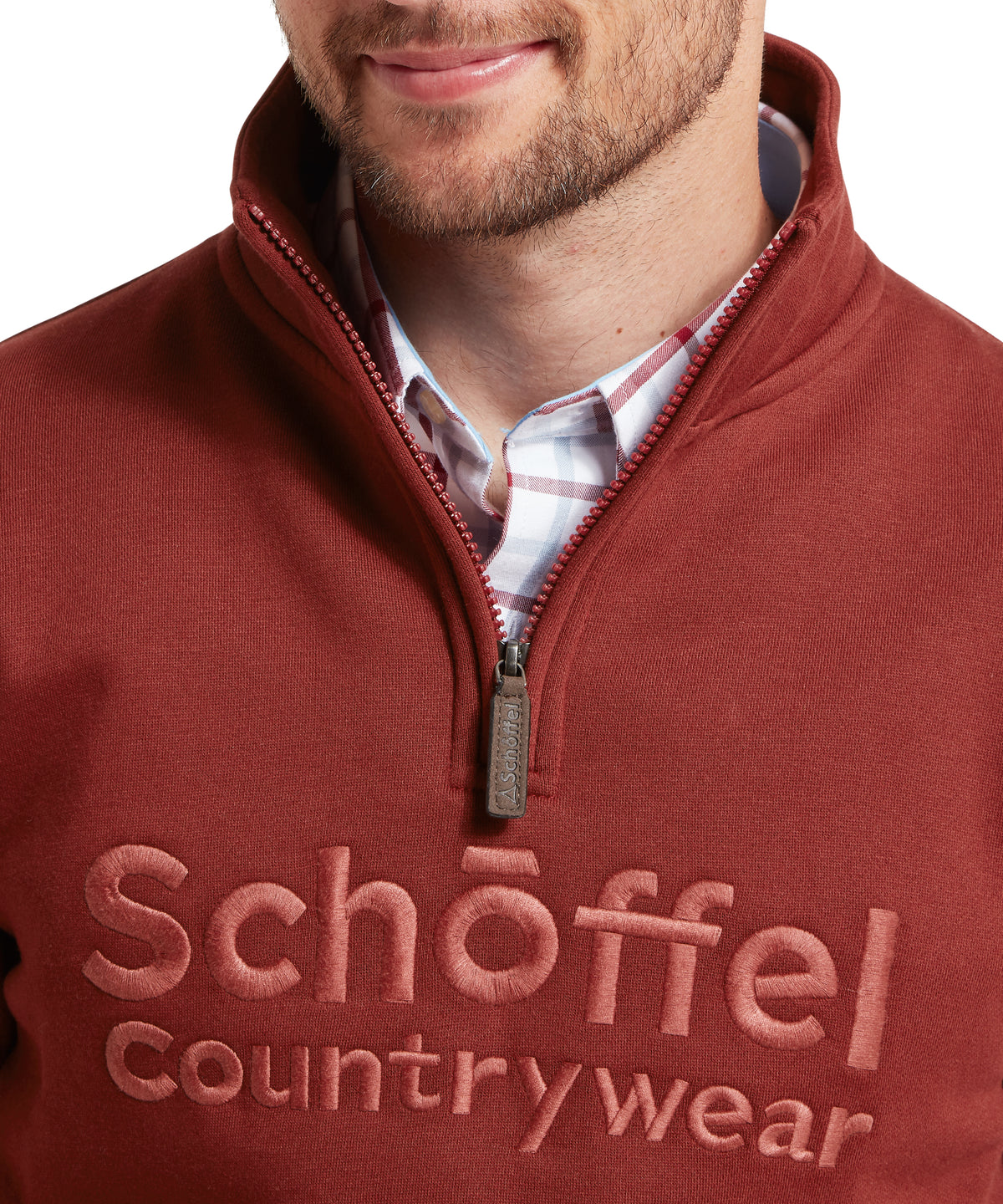 A rich rust-colored schoffel quarter-zip sweatshirt with textured knit fabric and embroidered