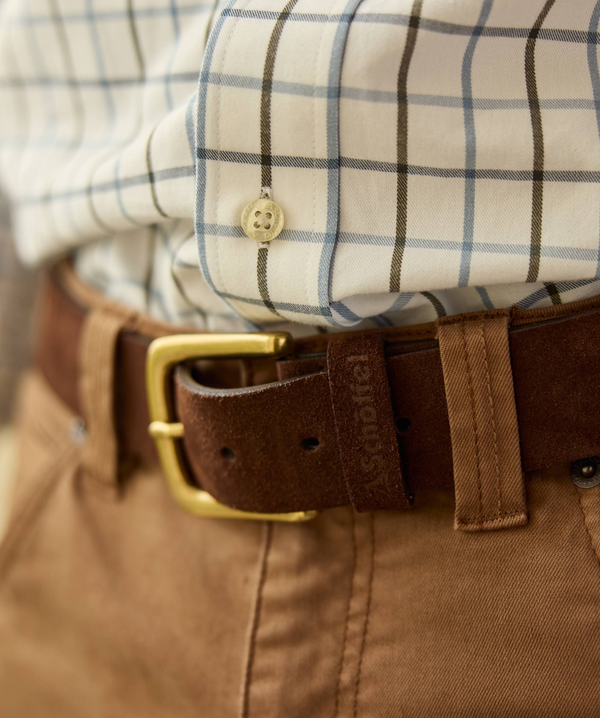 Close-up of a checked shirt with a brown belt and gold buckle.