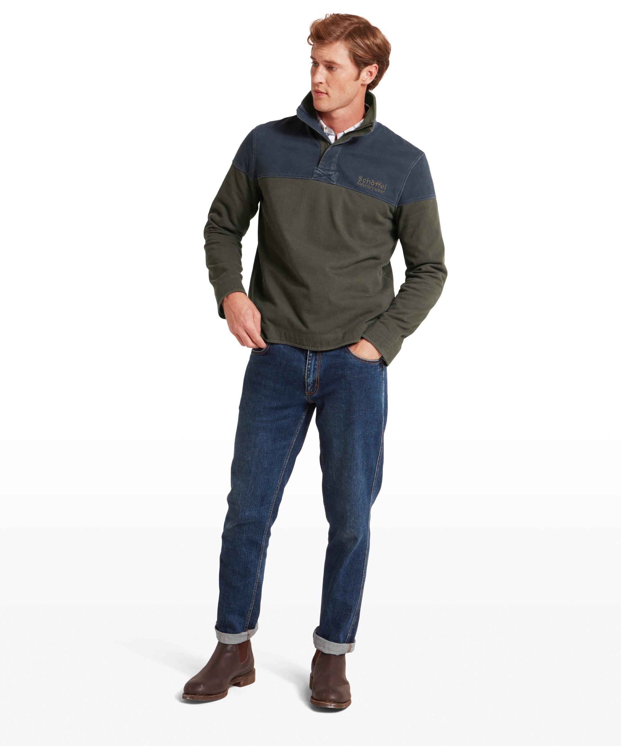 Man wearing a green and navy sweatshirt with blue jeans on a white background