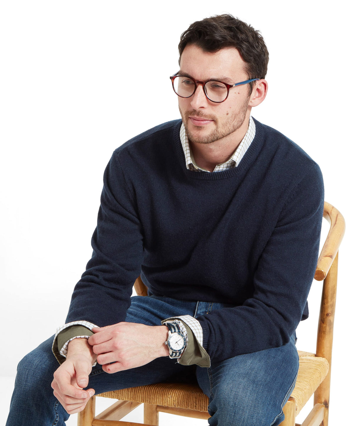 Navy lambswool crew neck jumper with ribbed cuffs and collar worn over a plaid collared shirt