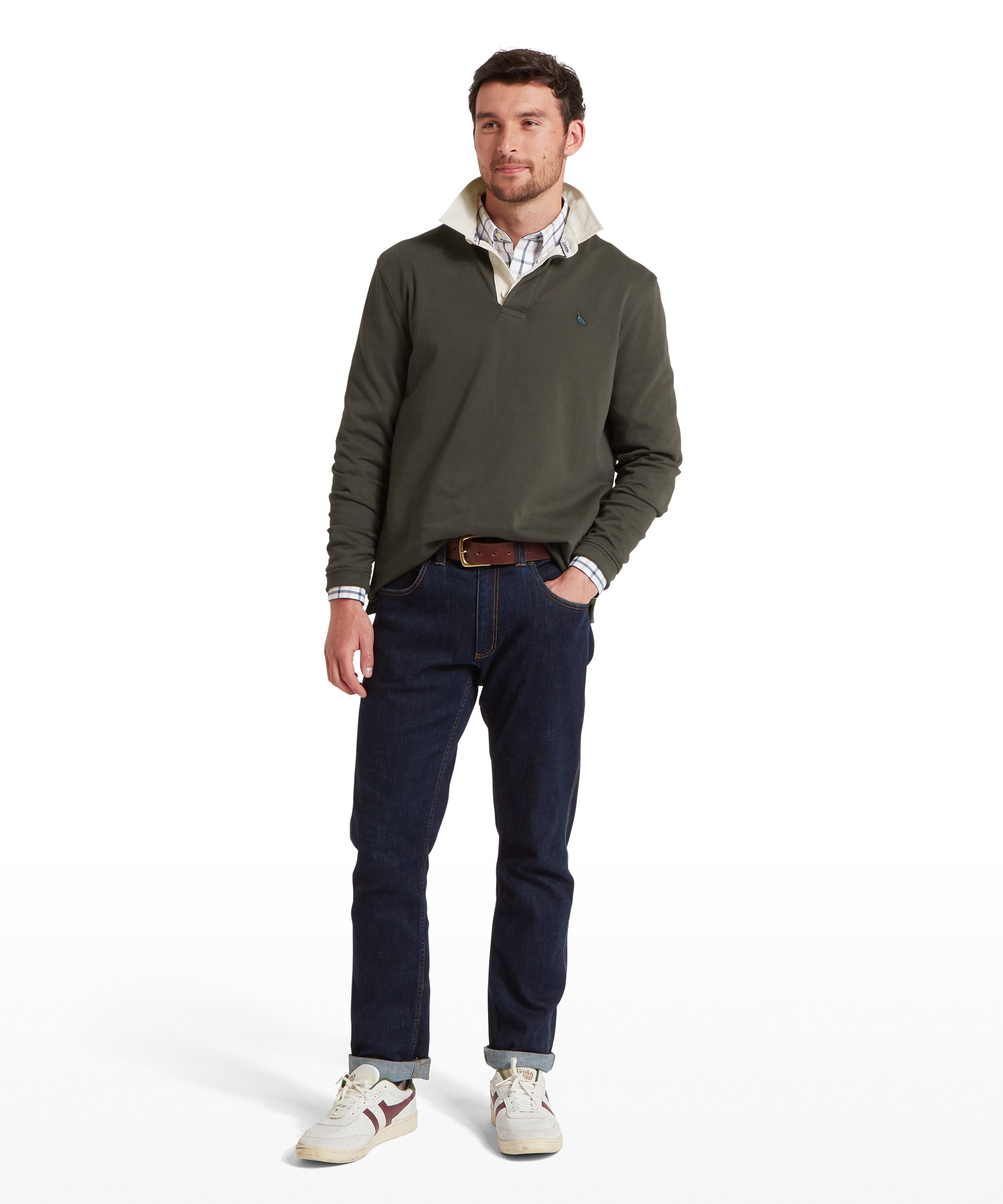 Man wearing a green sweatshirt, dark navy jeans, and white trainers on a white background