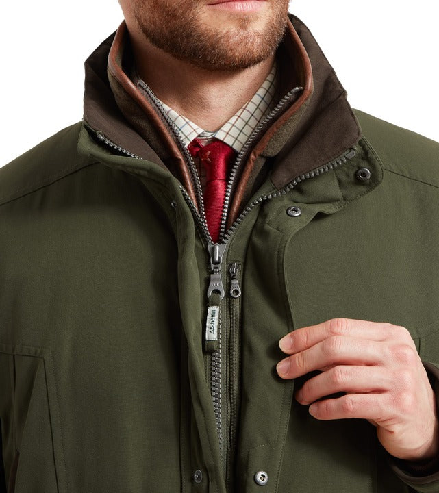 Schöffel Ptarmigan classic coat in green, close-up of contrast suede-effect collar and full-length zip with branded pull tag, styled with checked shirt and tie
