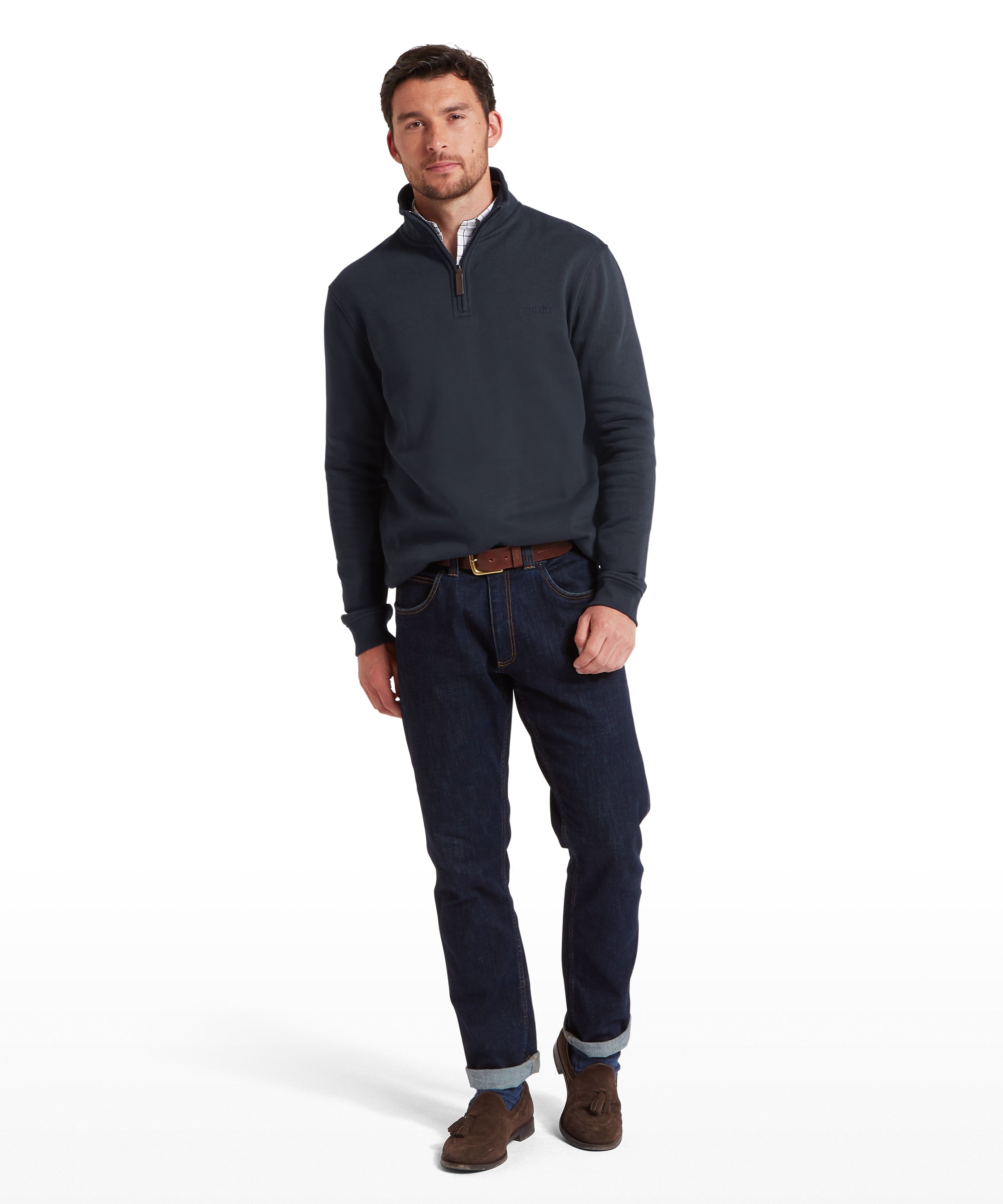 Man wearing a navy sweater and dark jeans on a white background