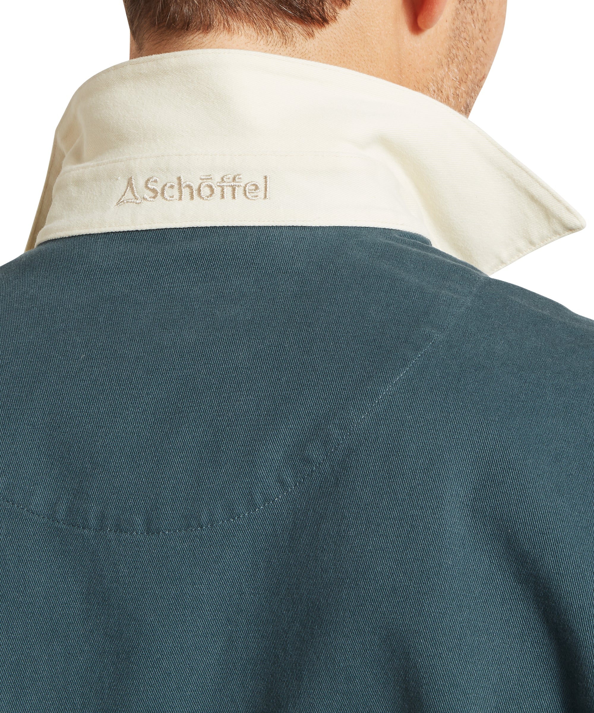 A cream-colored collar with aschöffel embroidered in dark thread on a teal cotton polo truro deck
