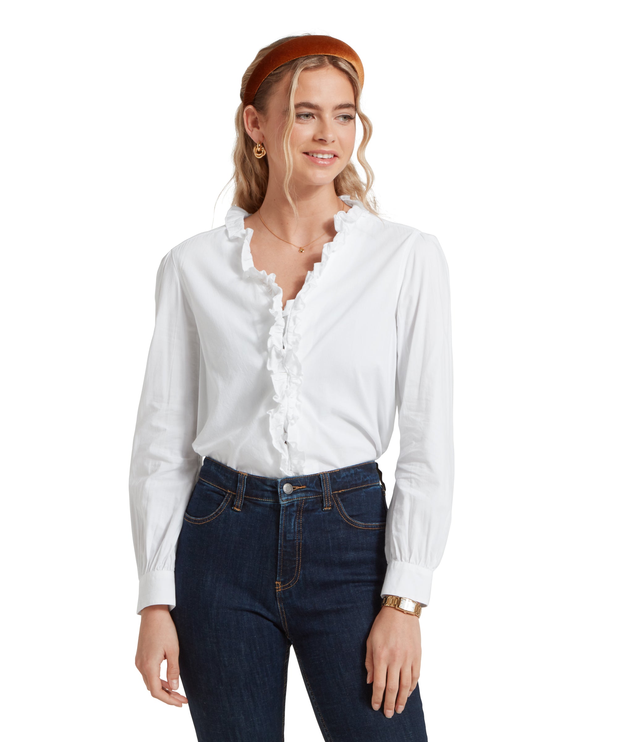 Close-up of a female model wearing a white Schöffel shirt, paired with dark denim jeans and gold accessories.