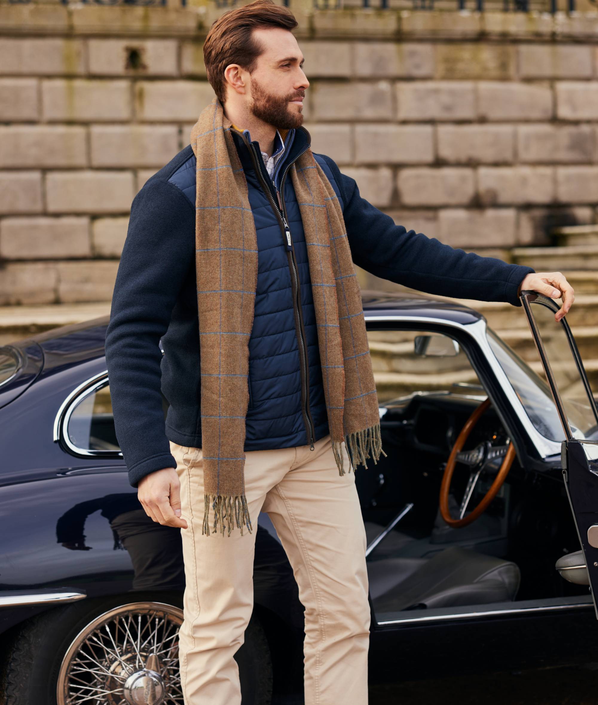Man with a scarf standing next to a vintage car
