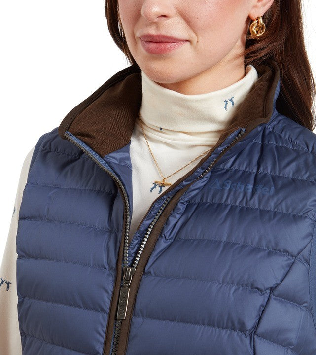 Close-up of a person wearing a blue puffer gilet over a white turtleneck.