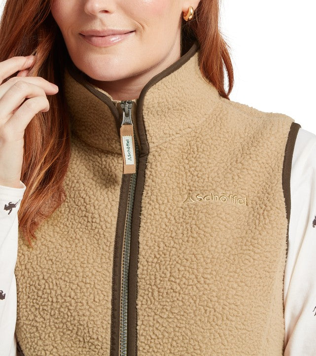 Close-up of a person wearing a beige fleece gilet with a Schoffel logo on a white background