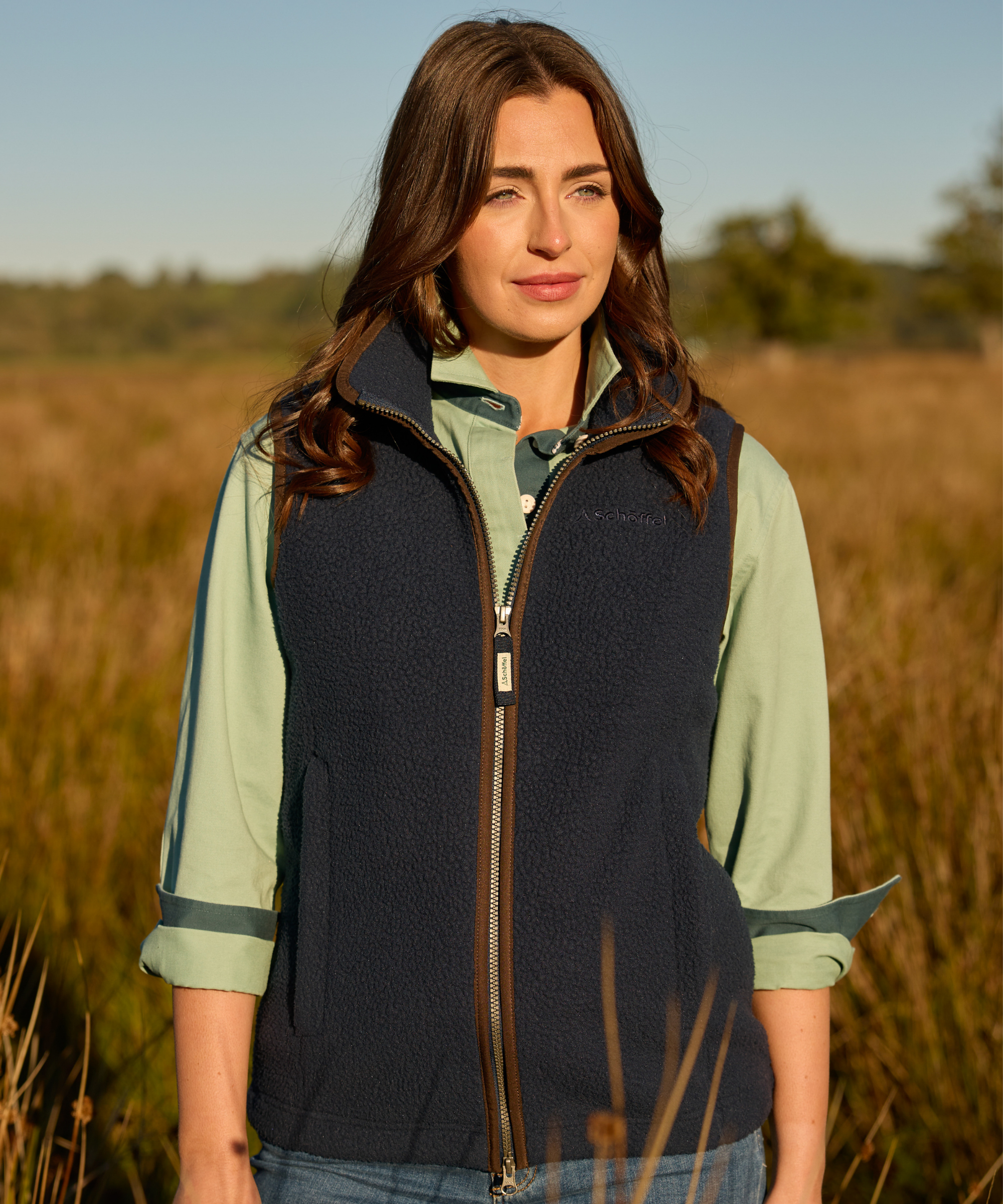 Woman wearing a navy vest over a light green shirt in a field