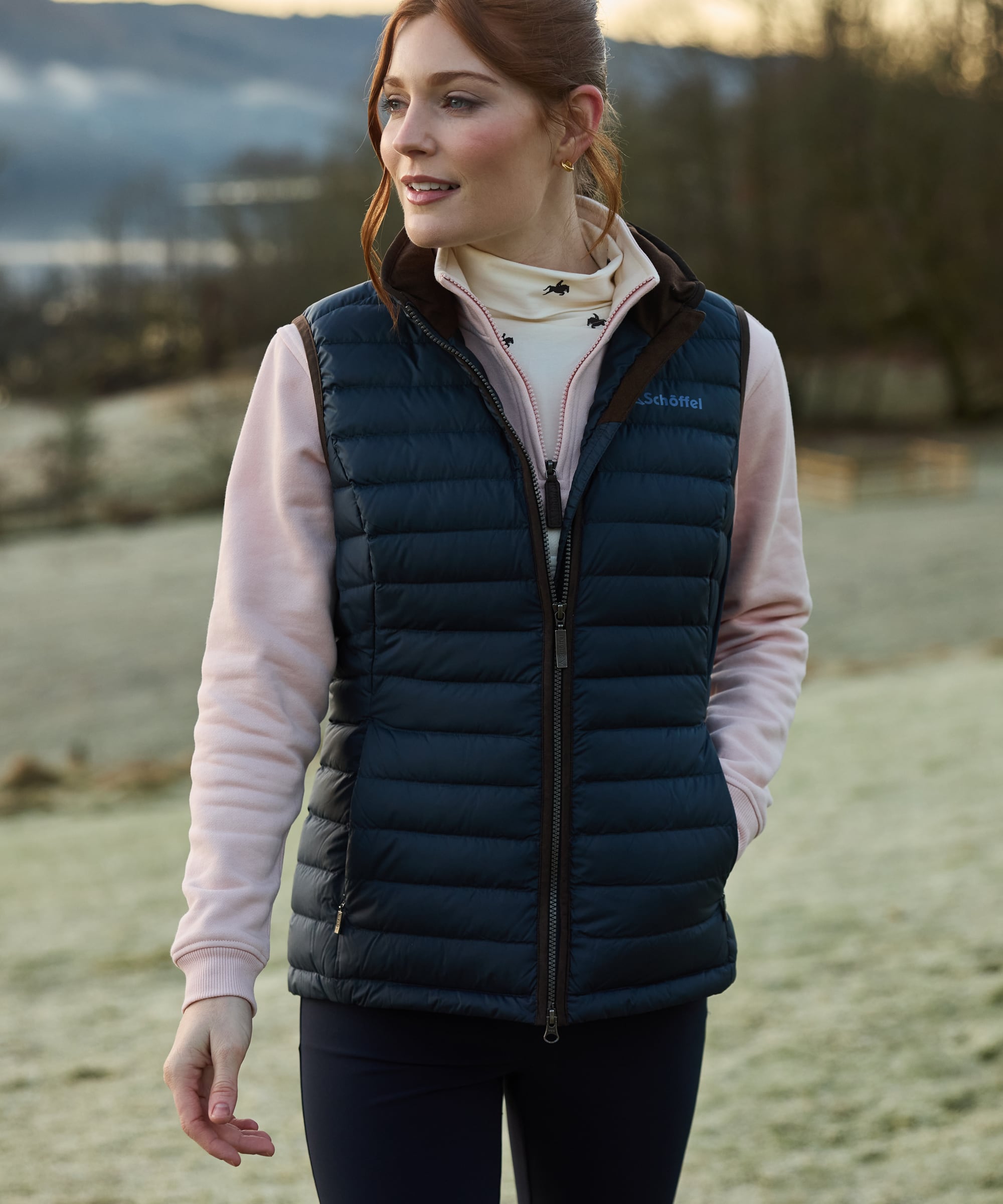 Woman wearing a navy gilet over a pink sweatshirt in an outdoor setting