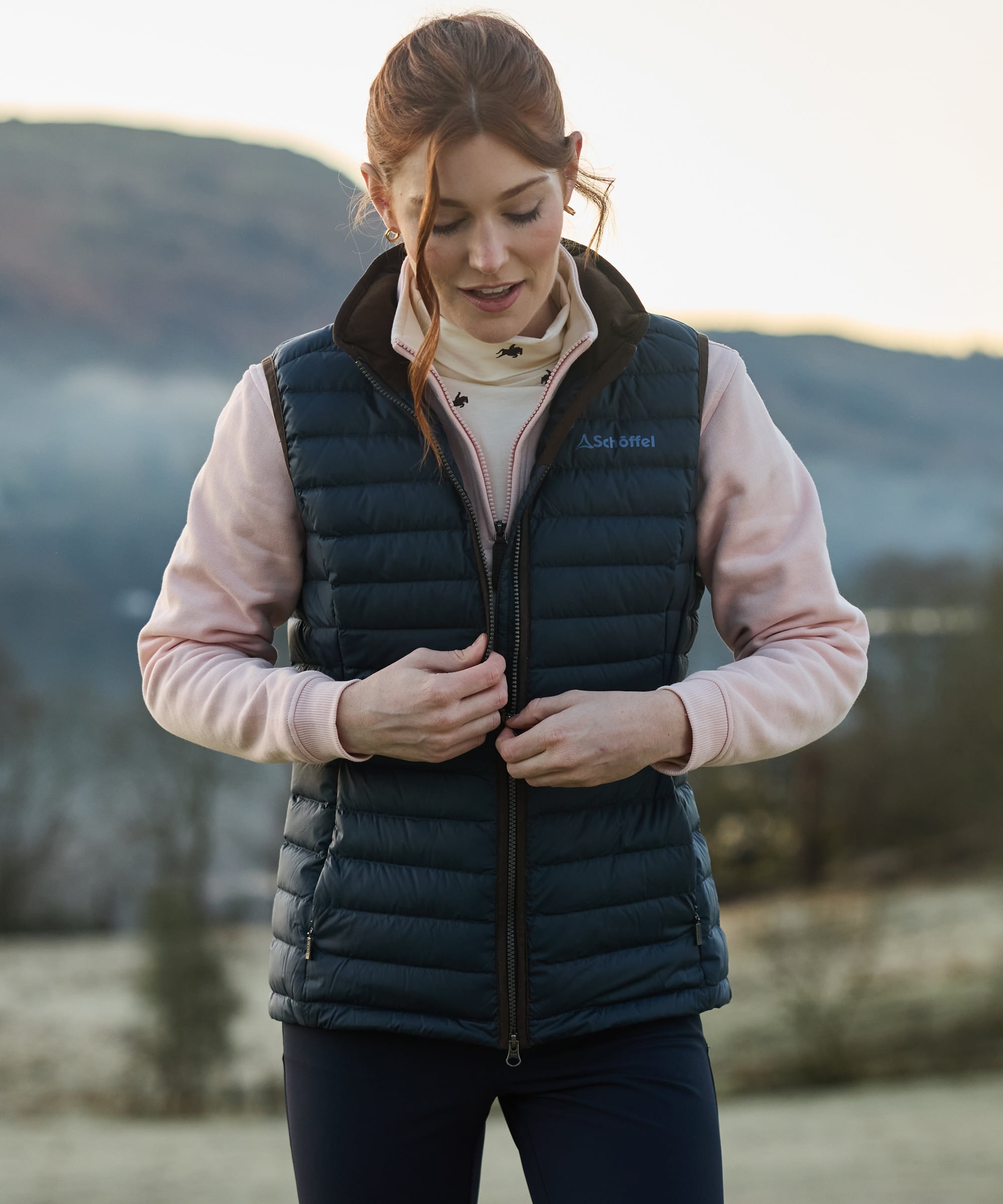 Woman wearing a blue gilet vest with a mountainous background