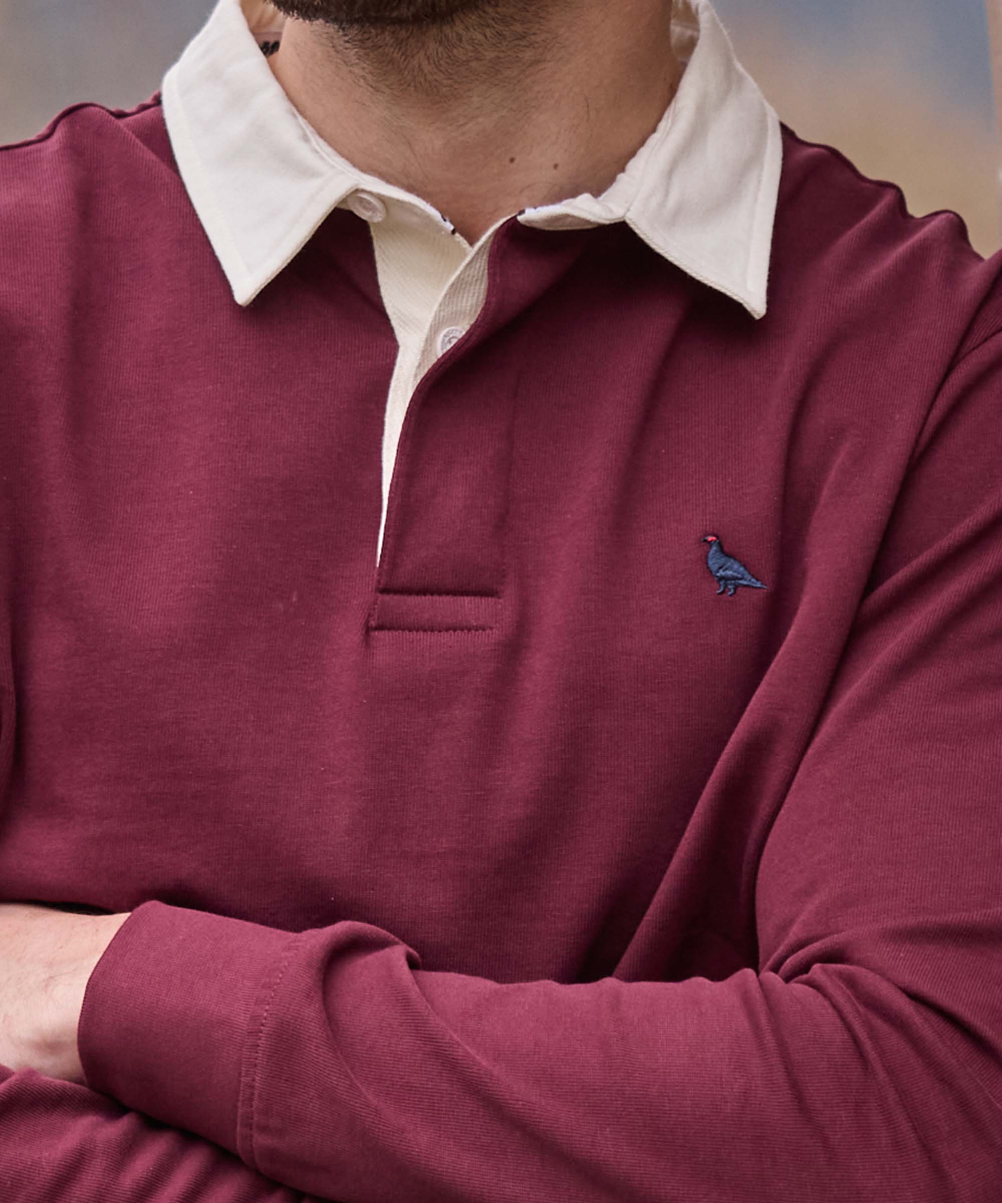 Close-up of a burgundy rugby shirt's cream collar and embroidered game bird detail