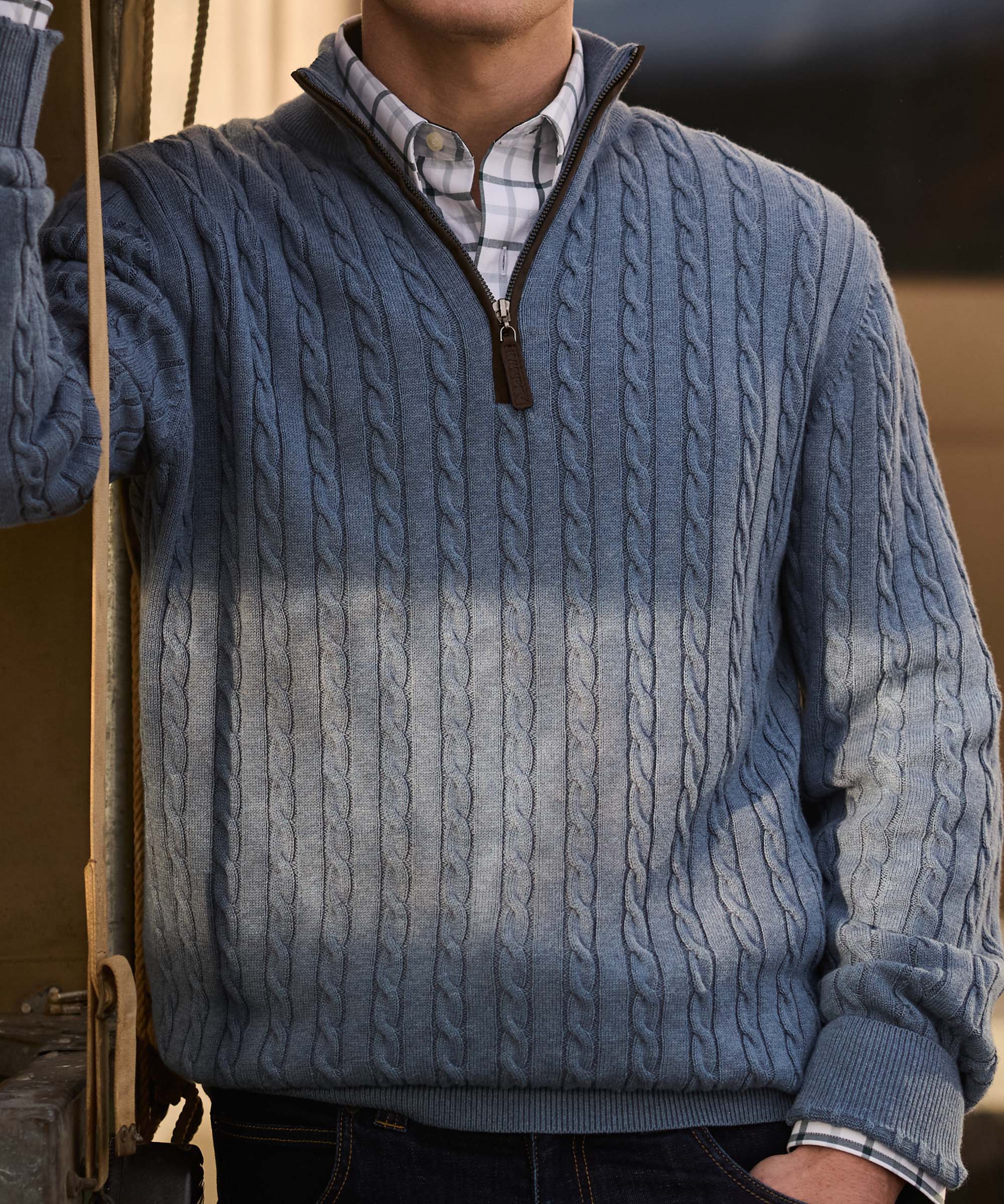 Man wearing a dip-dyed blue cable knit quarter-zip jumper with denim jeans and a check shirt