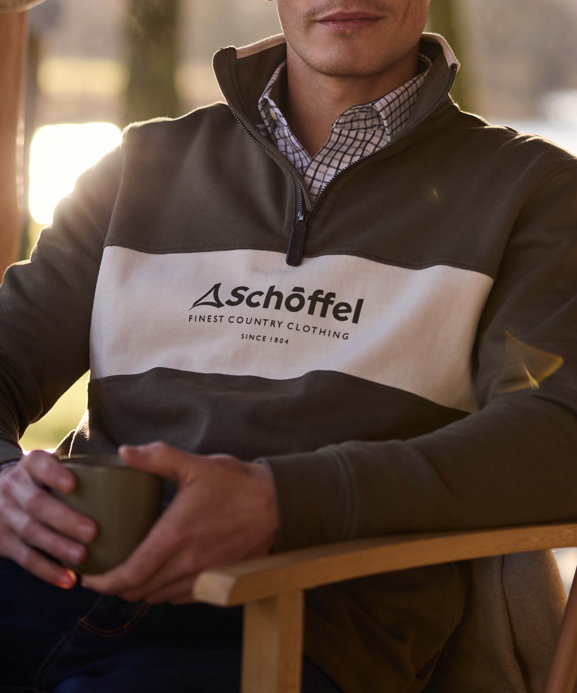 Close-up of a khaki and cream colour-block quarter-zip jumper with Schöffel Finest Country Clothing branding