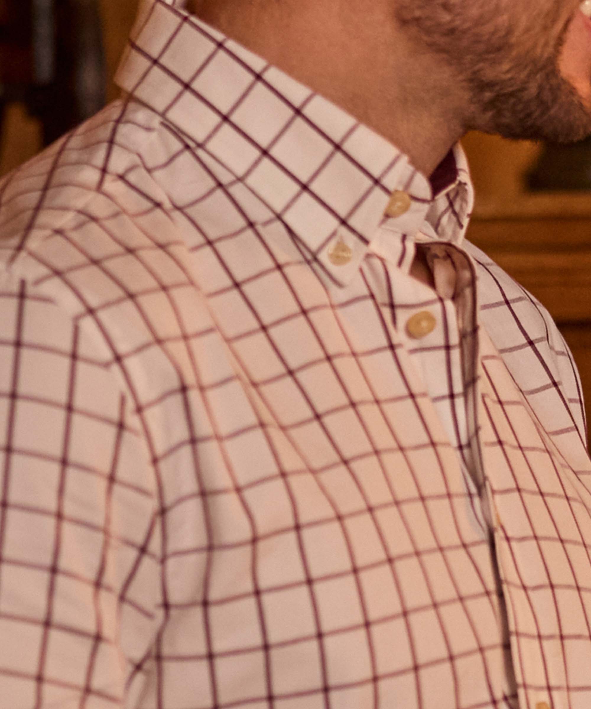 Close-up of a white and burgundy windowpane check shirt collar and button placket