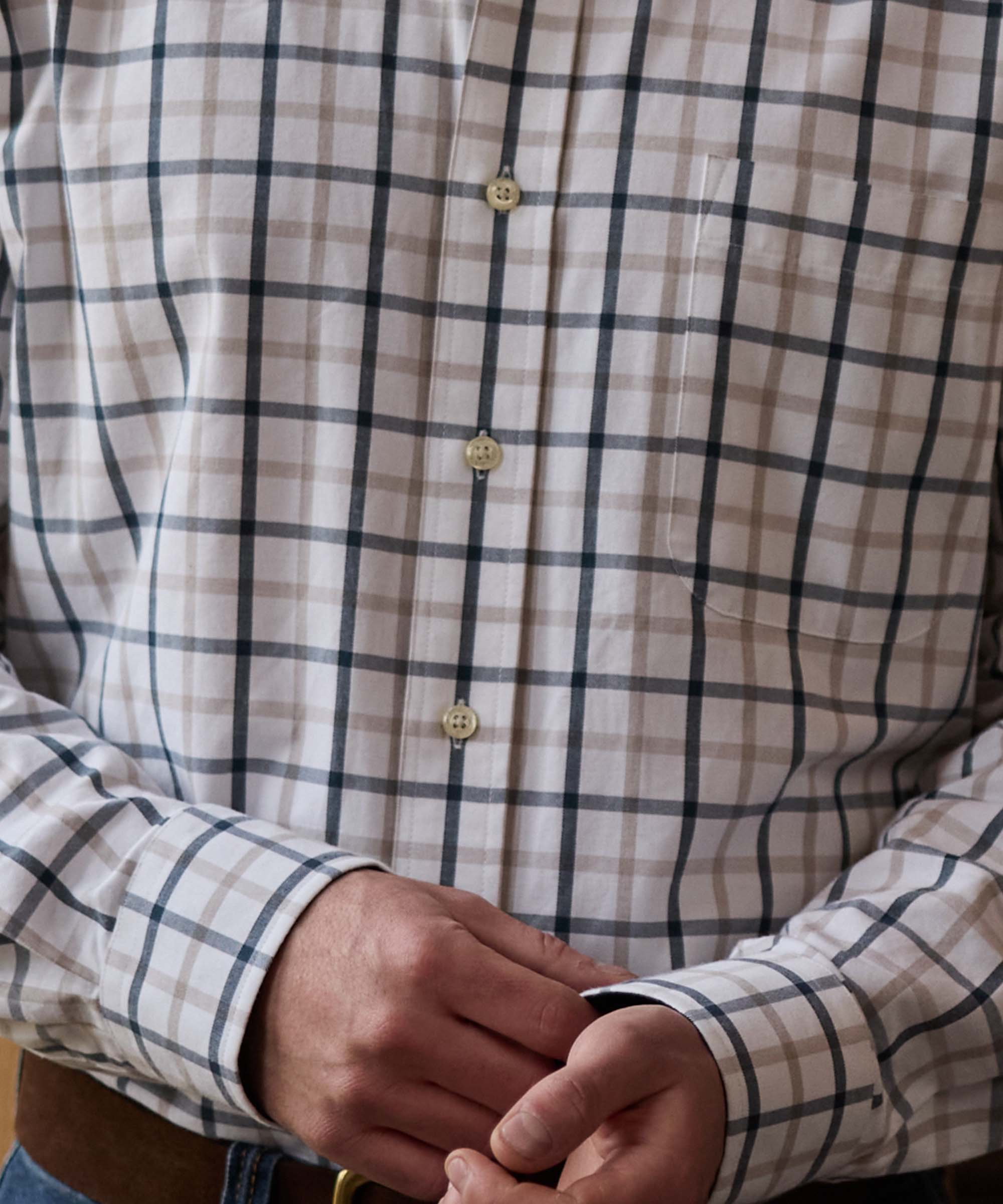 Close-up of a beige and navy check shirt's button placket and chest pocket detail