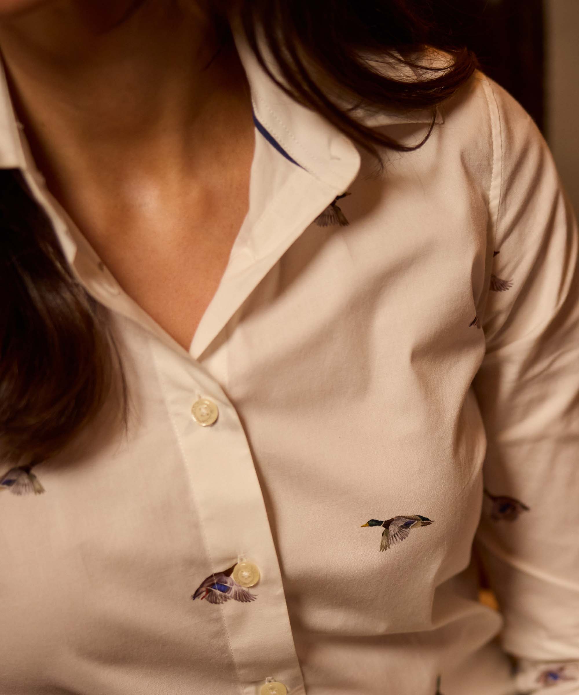 Close-up of a white shirt with a flying mallard duck print, showing the collar and button placket
