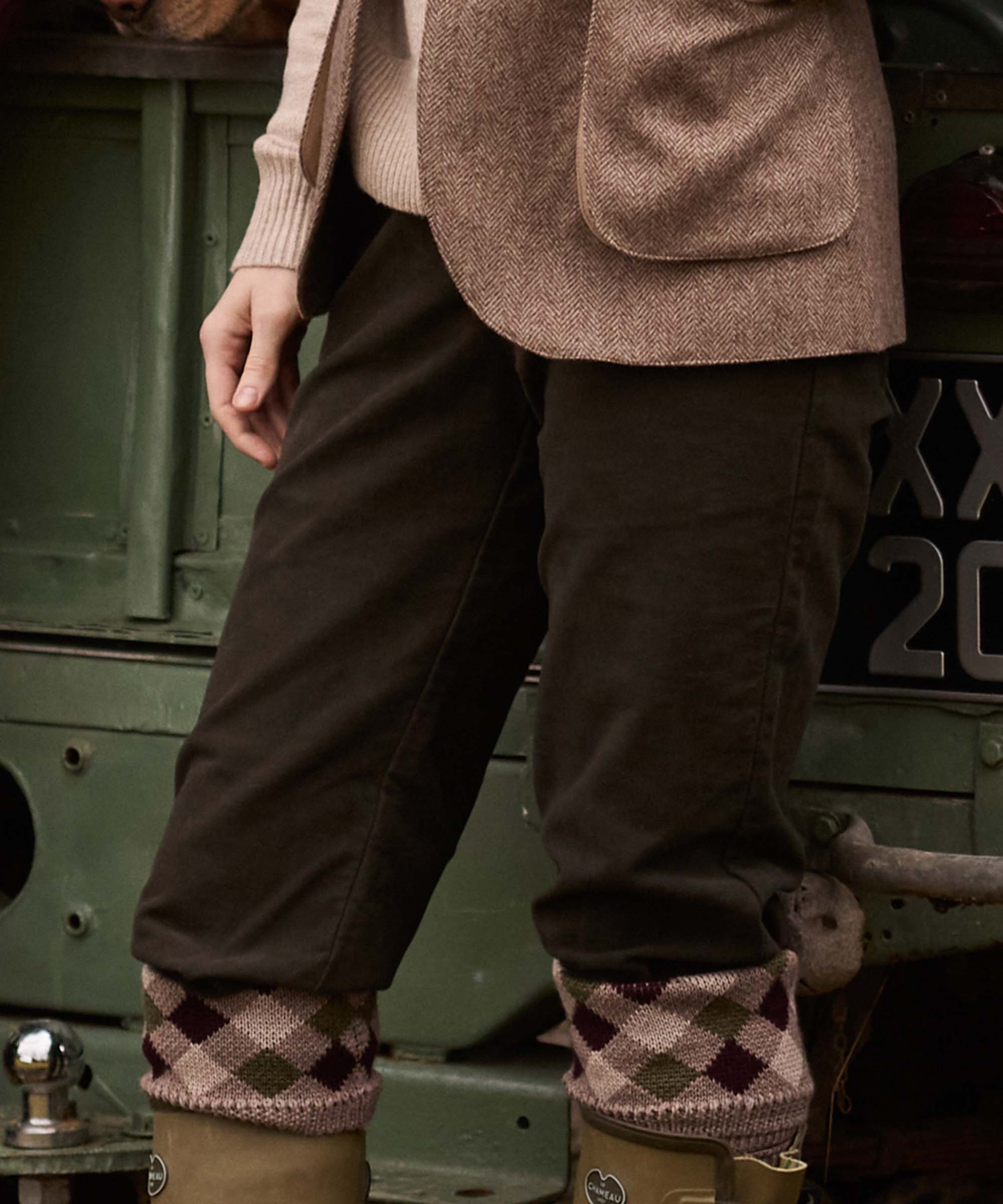 Close-up of tweed jacket pockets over brown corduroy trousers, tucked into Fair Isle sock garters and Le Chameau wellington boots