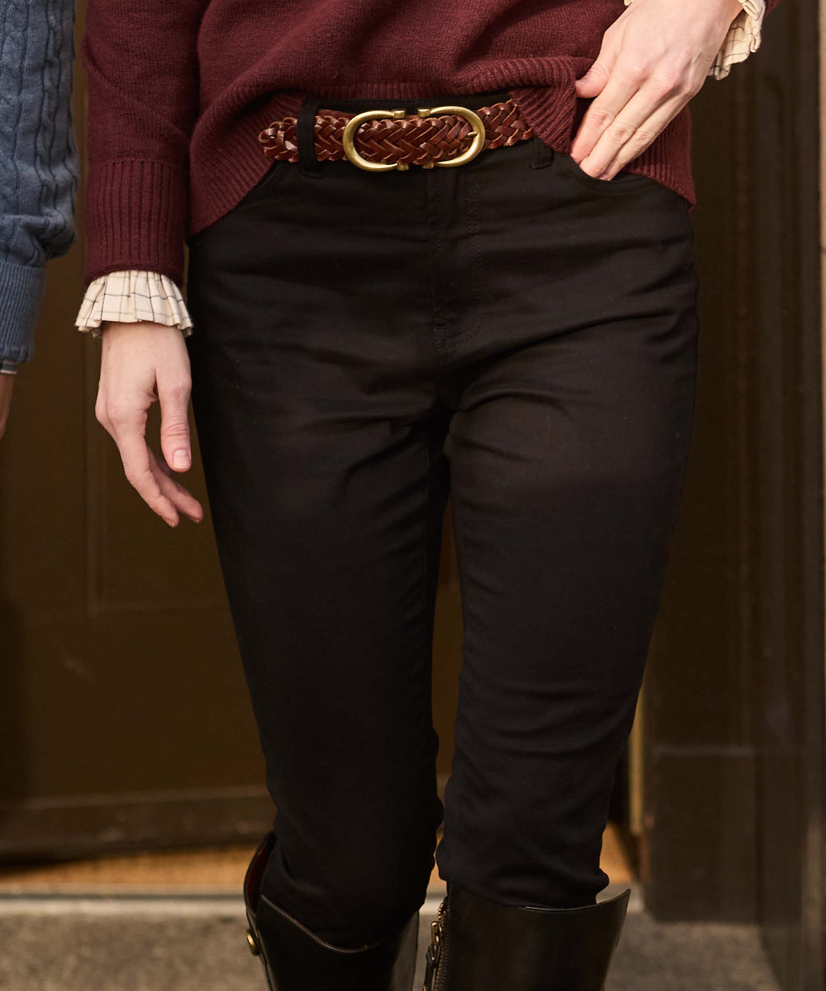 A braided brown leather belt with a gold toned oval buckle styled with black poppy jeans
