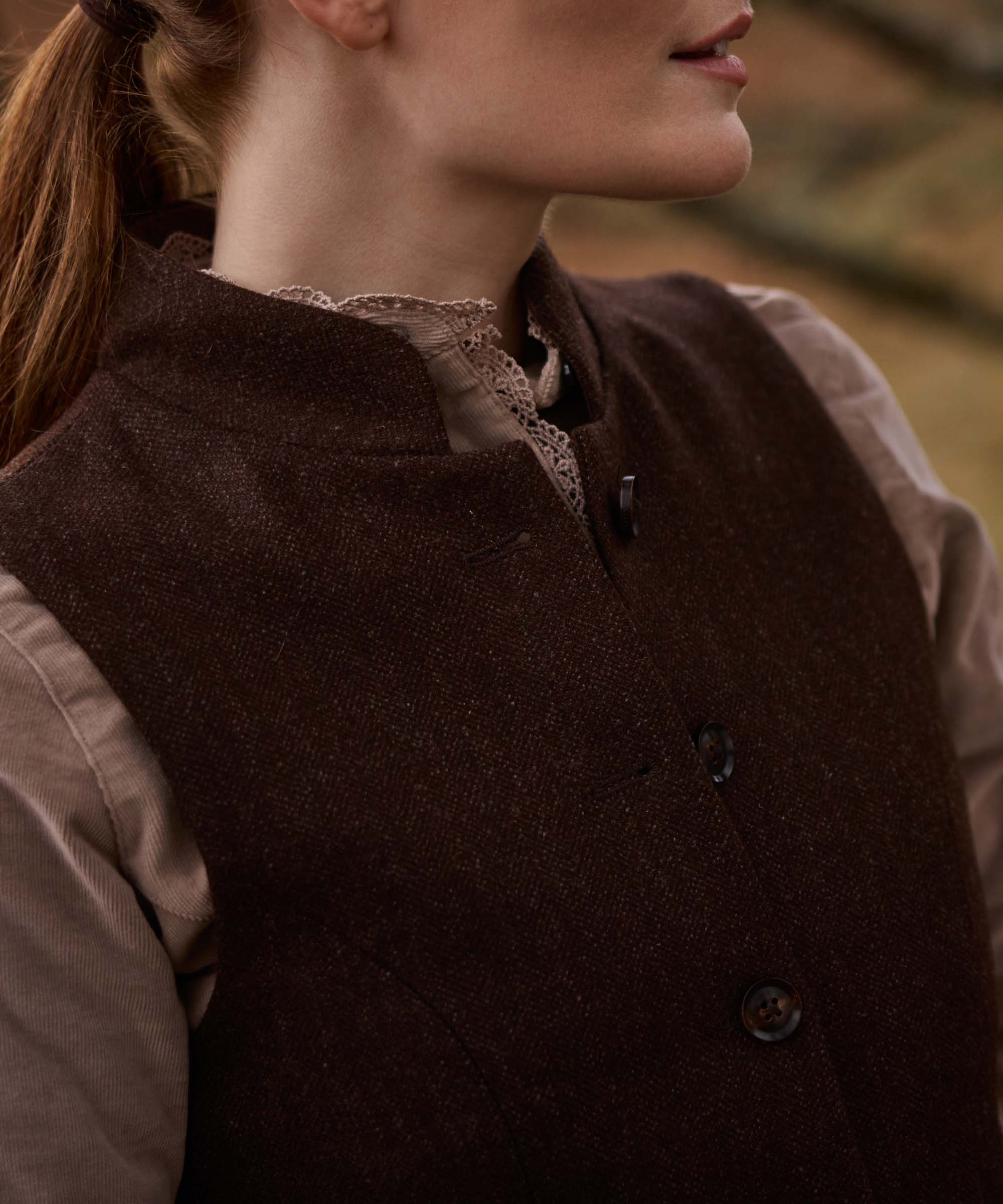 Close-up of the button fastening and stand collar on Schöffel Country's brown herringbone tweed gilet