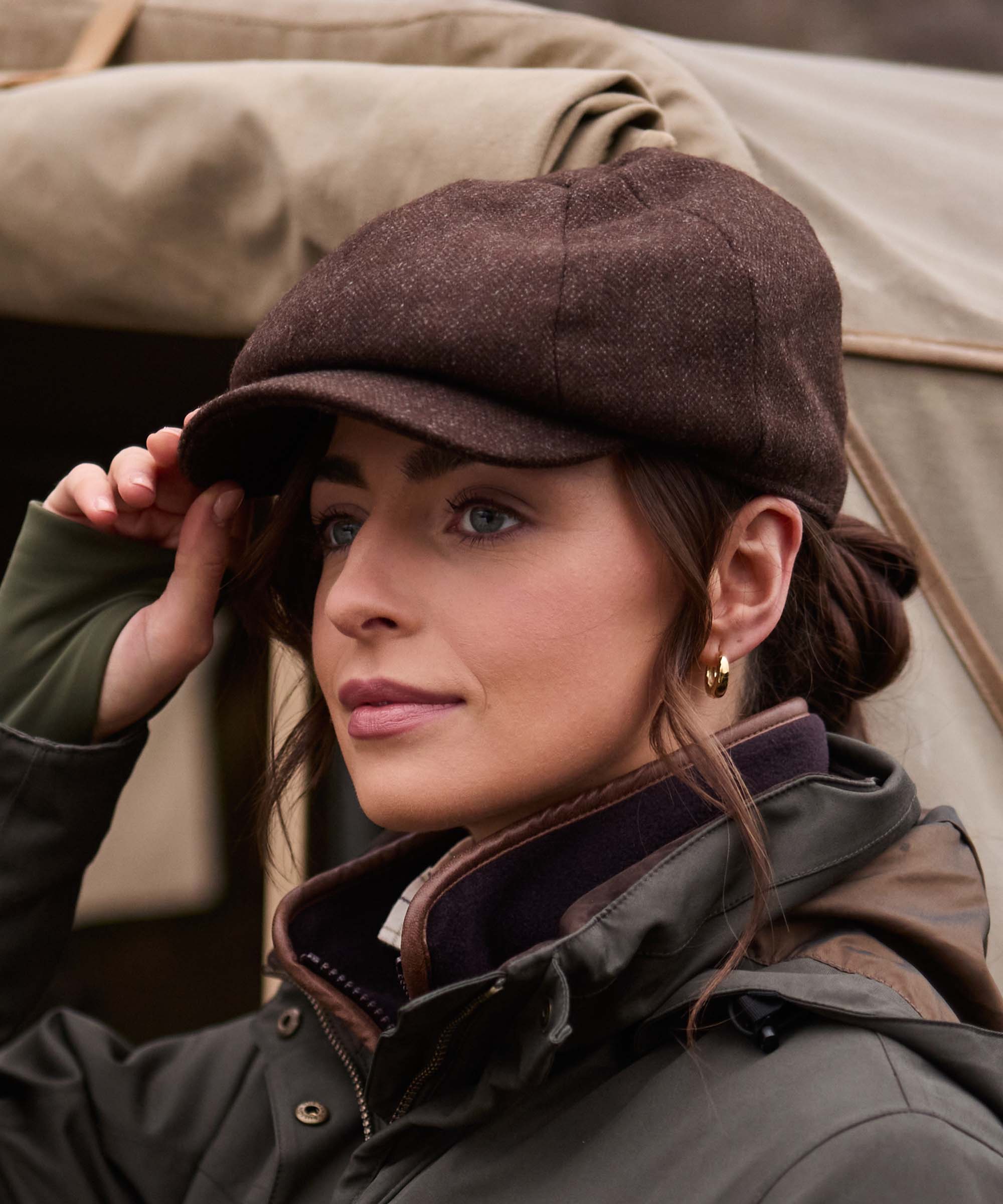Close-up of woman wearing Schöffel Country's brown herringbone tweed flat cap, adjusting the peak