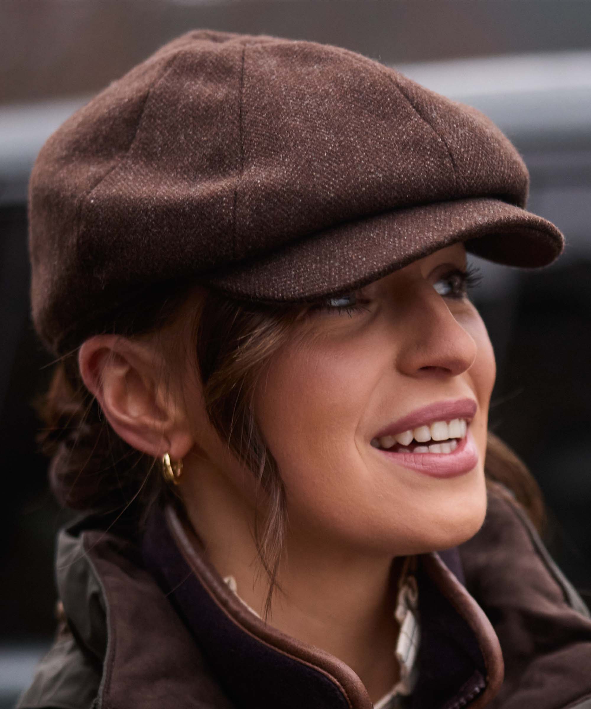 Close-up of woman smiling in Schöffel Country's brown herringbone tweed flat cap