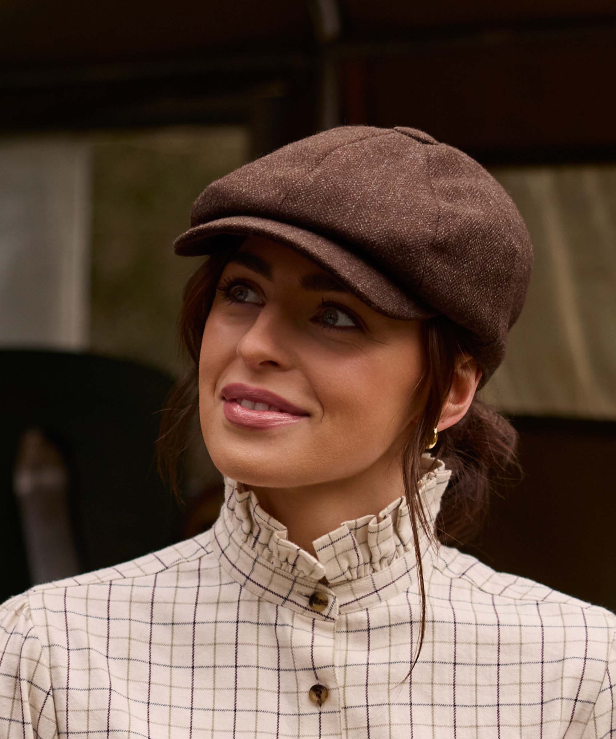 Woman wearing Schöffel Country's brown herringbone tweed flat cap with an olive wax jacket