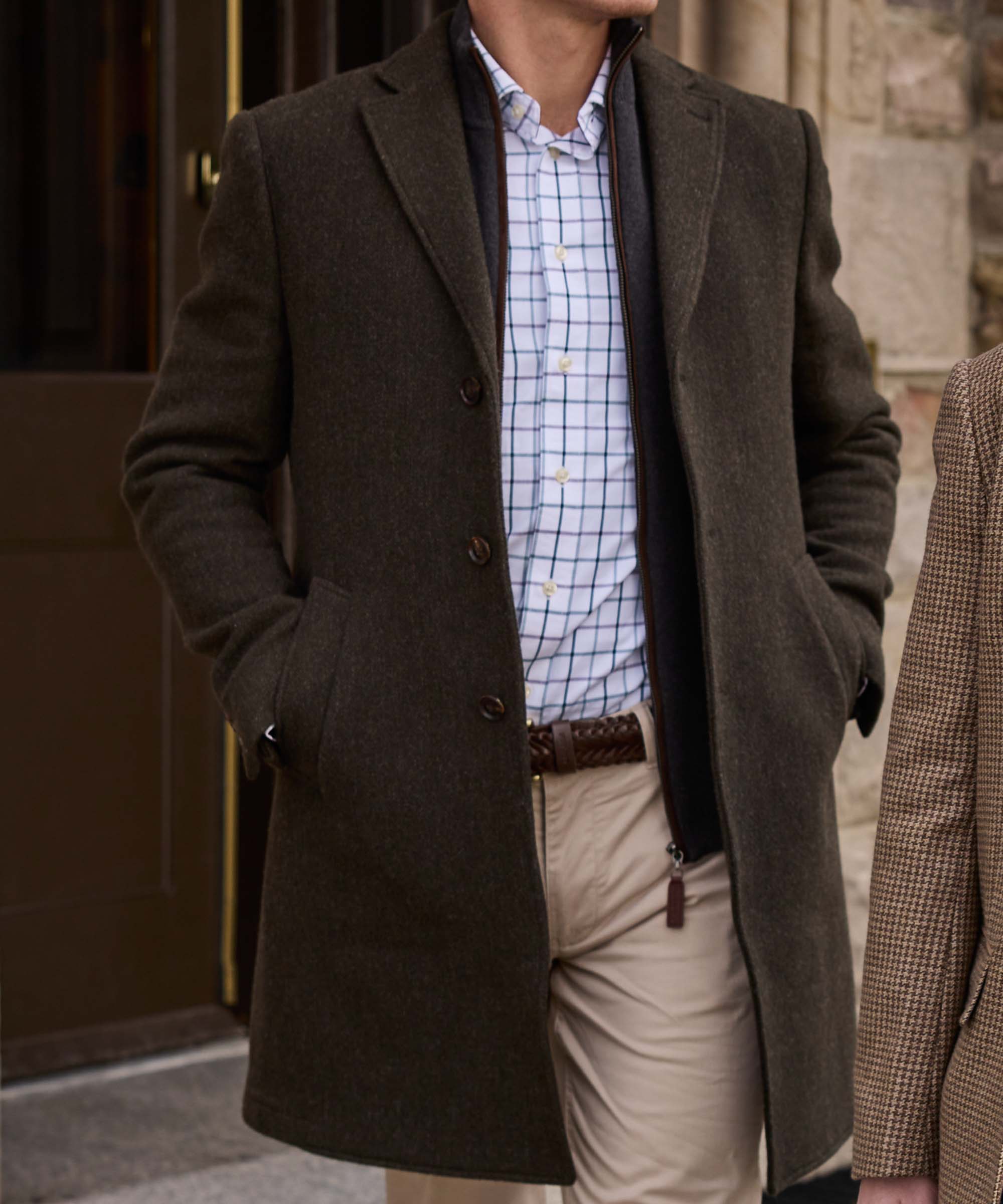 Close-up of Schöffel Country's khaki wool overcoat, worn open over a check shirt and chinos