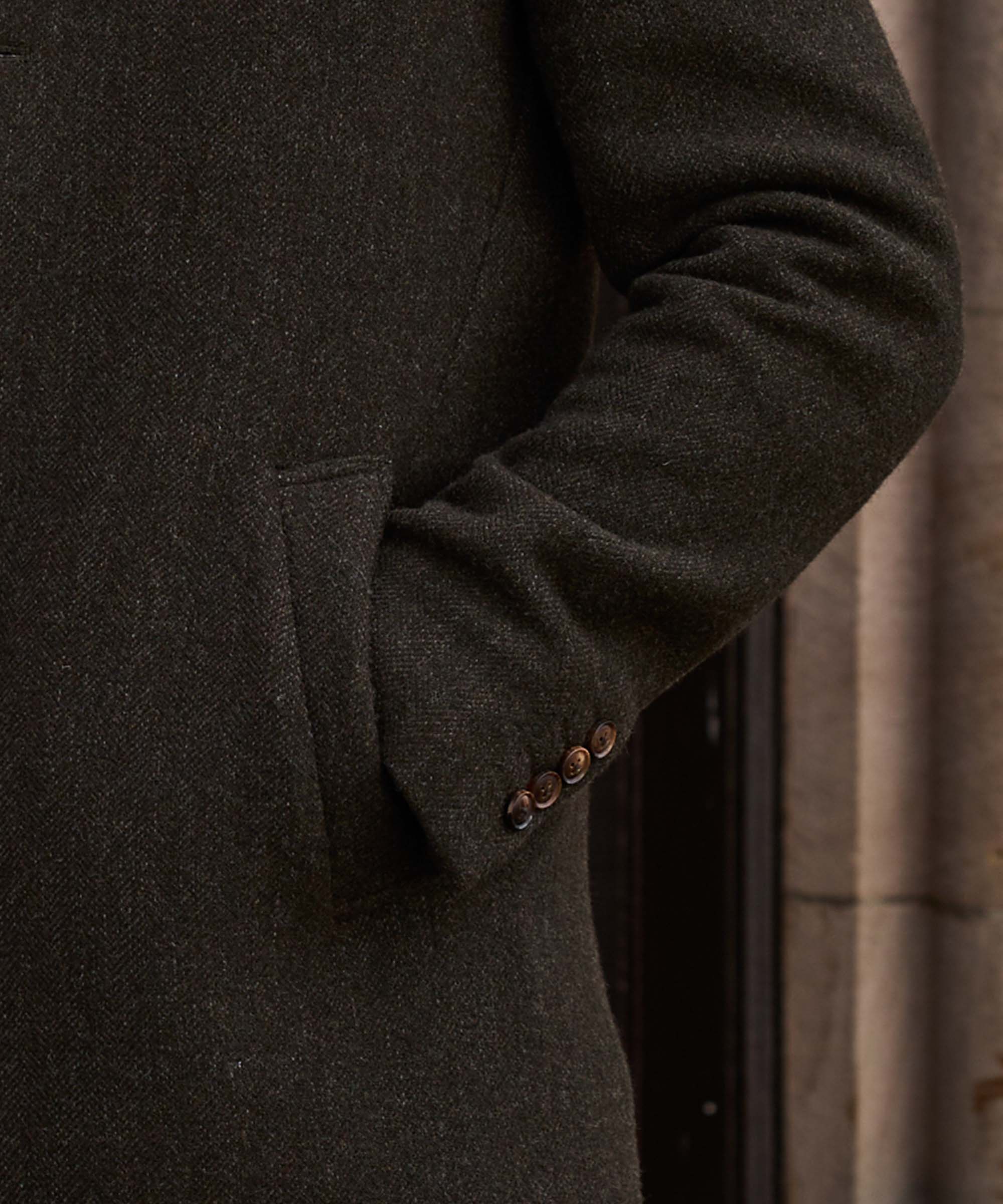 Close-up of the flap pocket and button detail on Schöffel Country's khaki wool overcoat