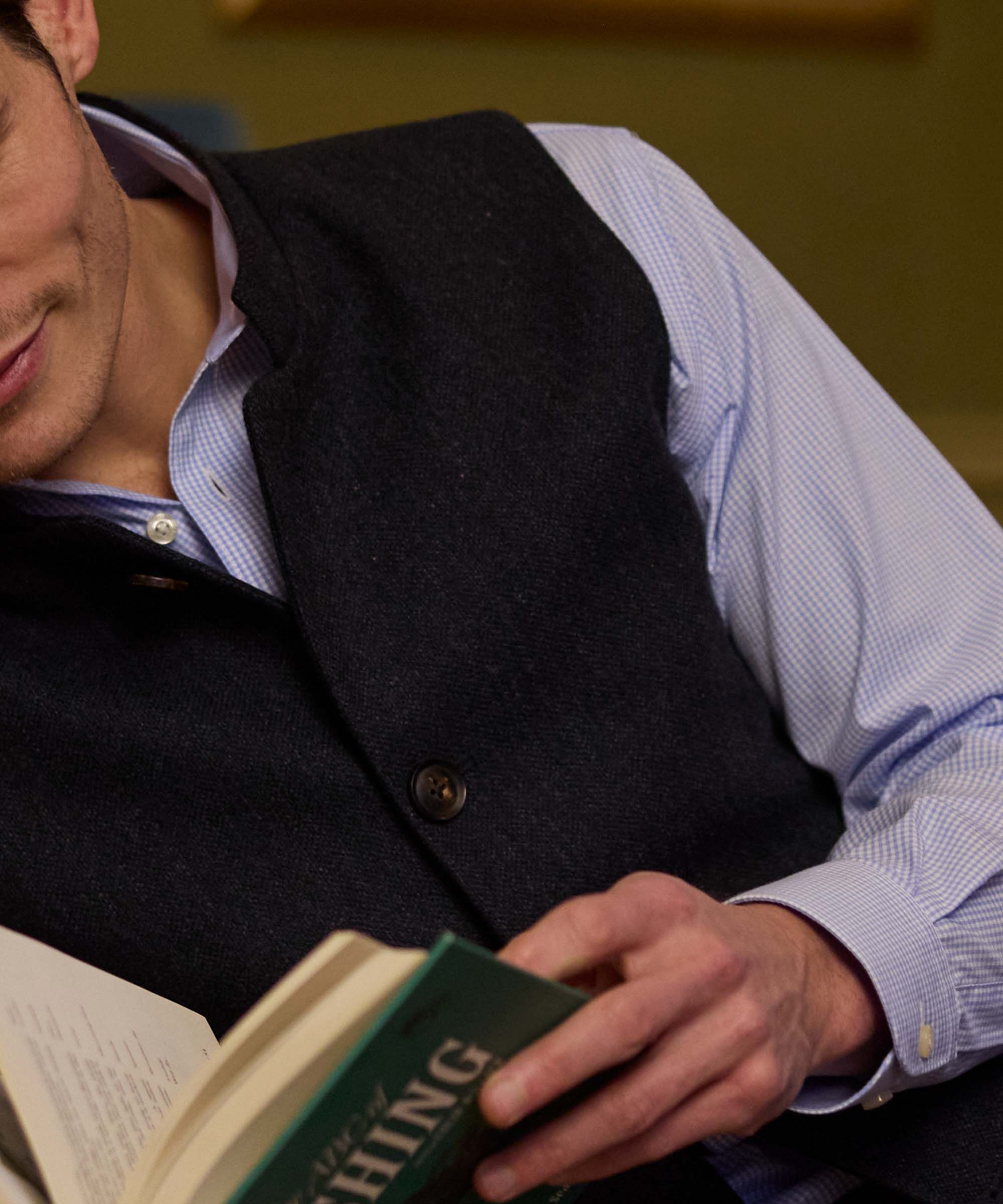 Close-up of Schöffel Country's charcoal wool gilet, worn over a gingham shirt while reading
