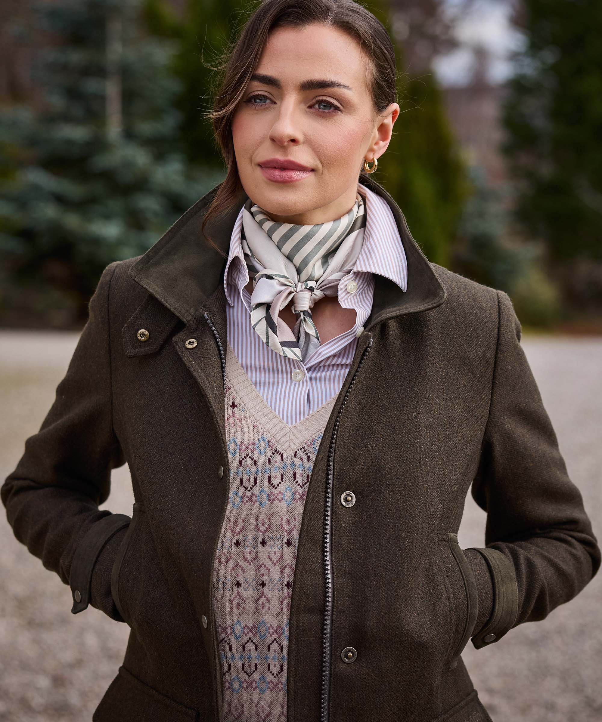Woman wearing Schöffel Country's khaki wool field coat with a striped silk scarf and Fair Isle jumper