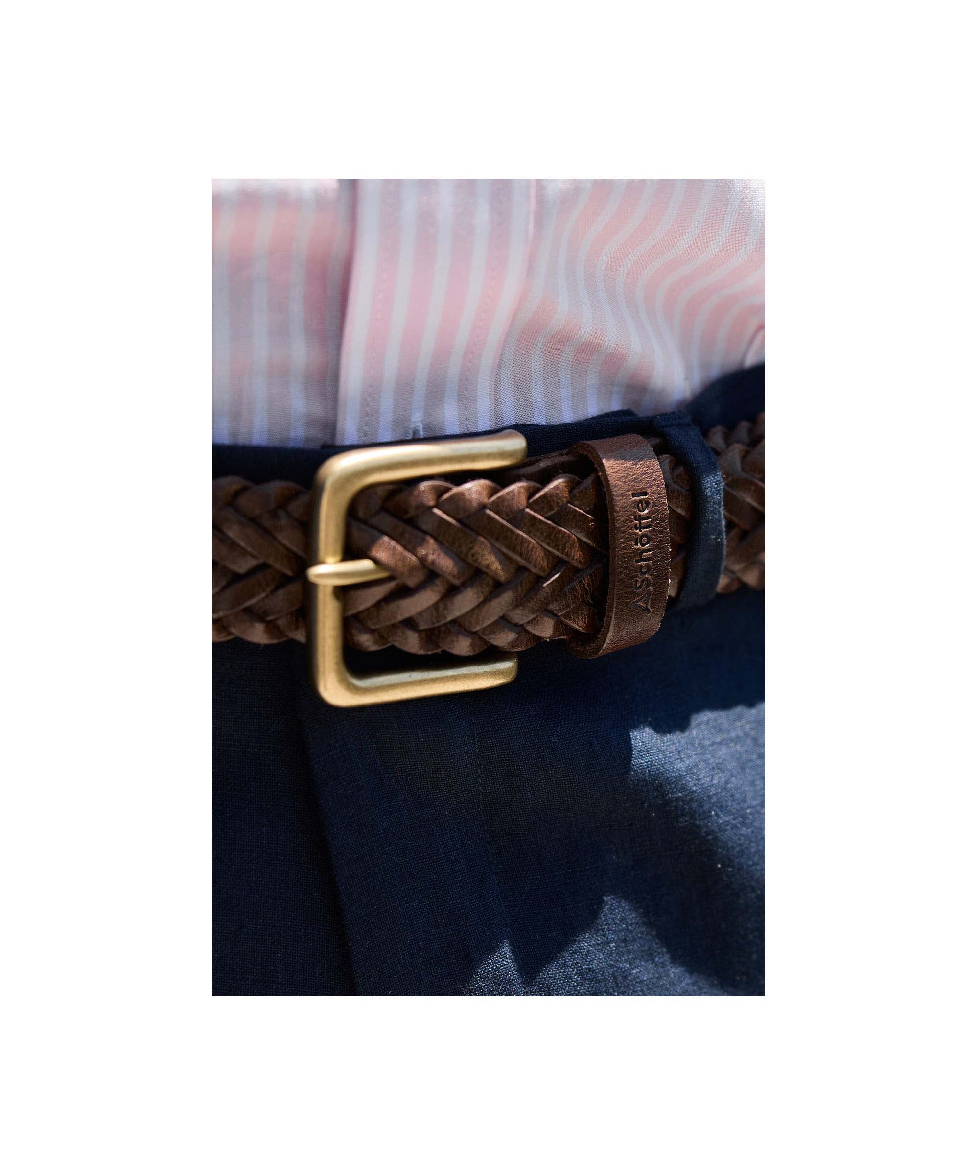 Brown braided belt with gold buckle worn by a person in a striped shirt and dark pants.