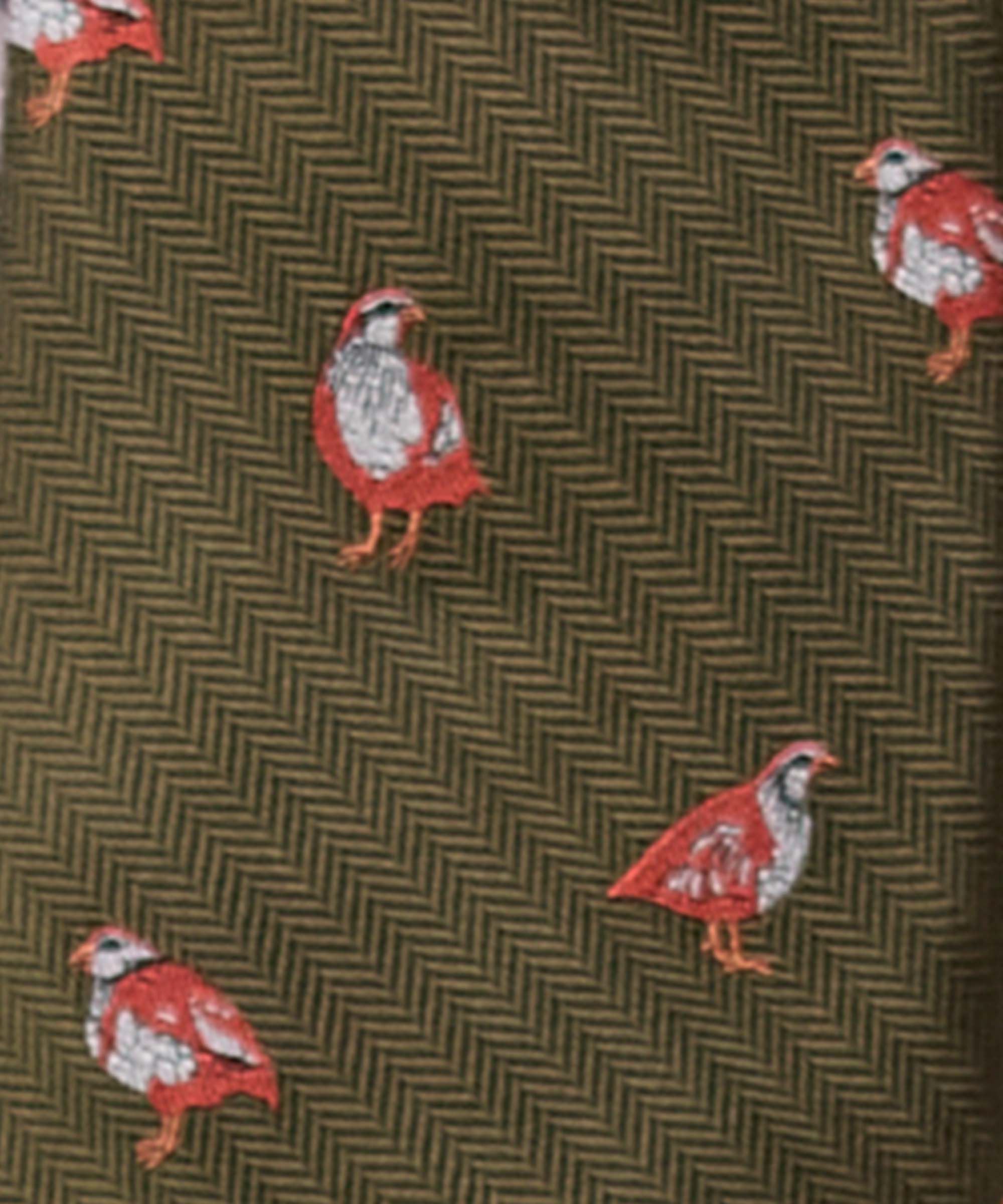Close-up of Schöffel Country's olive game bird print silk tie, showing the repeat partridge motif