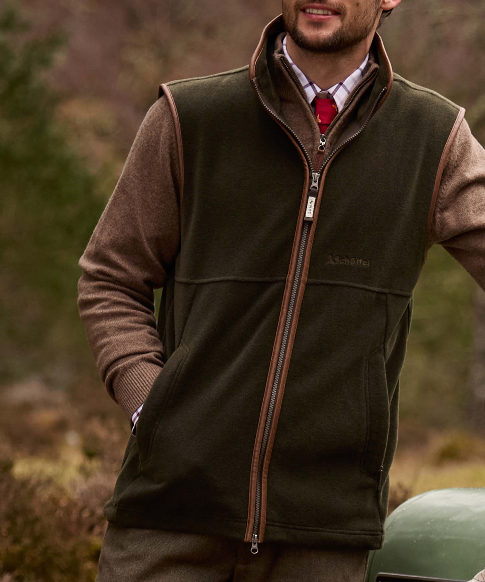 Man wearing Schöffel Country's khaki fleece gilet with leather trim, over a checked shirt and red tie