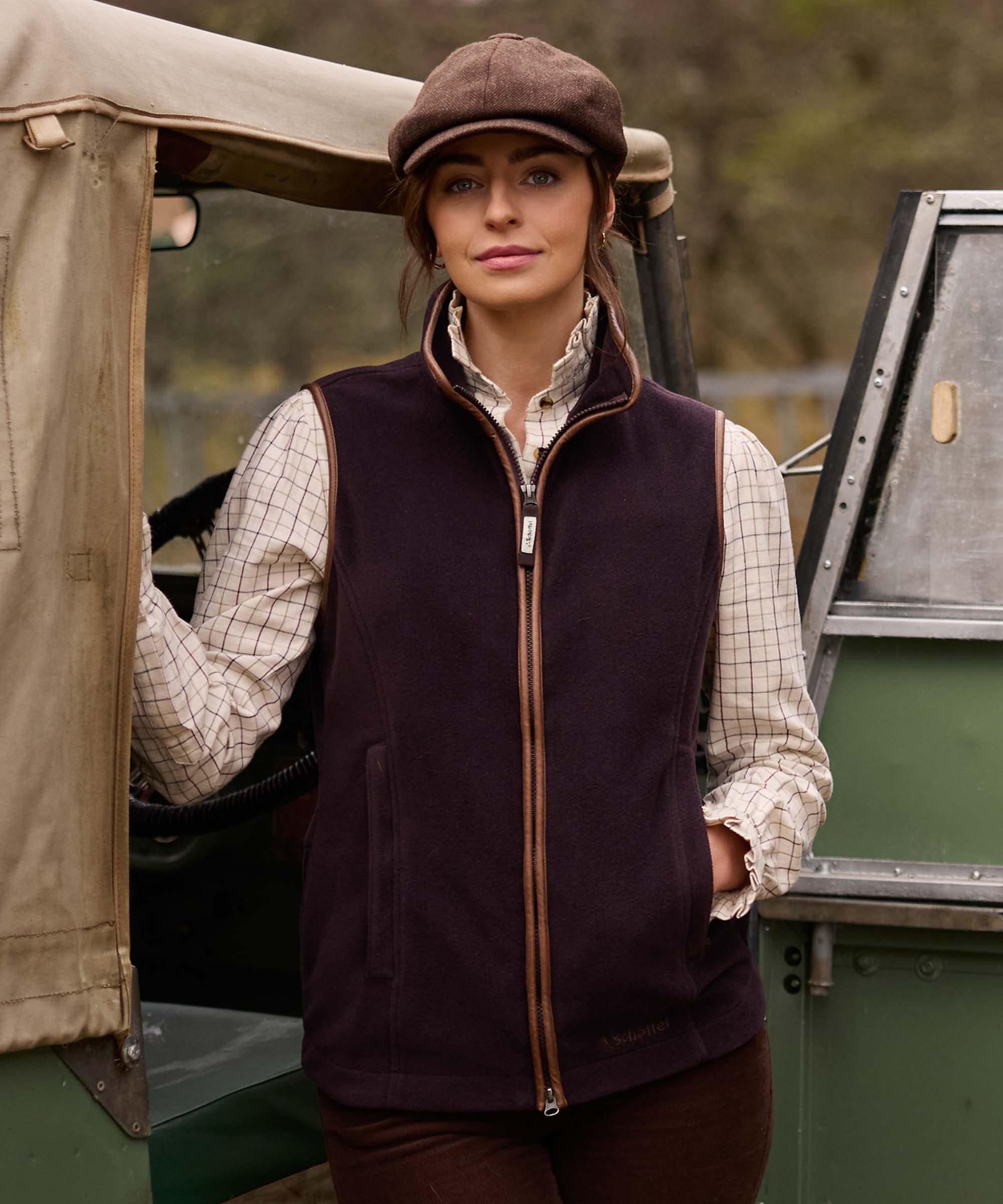 Woman wearing Schöffel Country's aubergine fleece gilet with leather trim, stood by a shooting brake