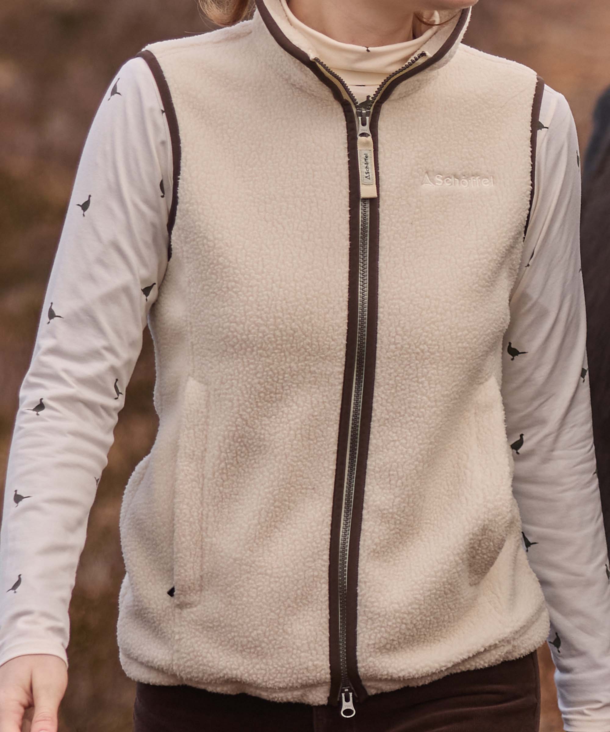 Close-up of a cream Schöffel sherpa fleece gilet with brown corduroy trim, worn over a pheasant-print top.