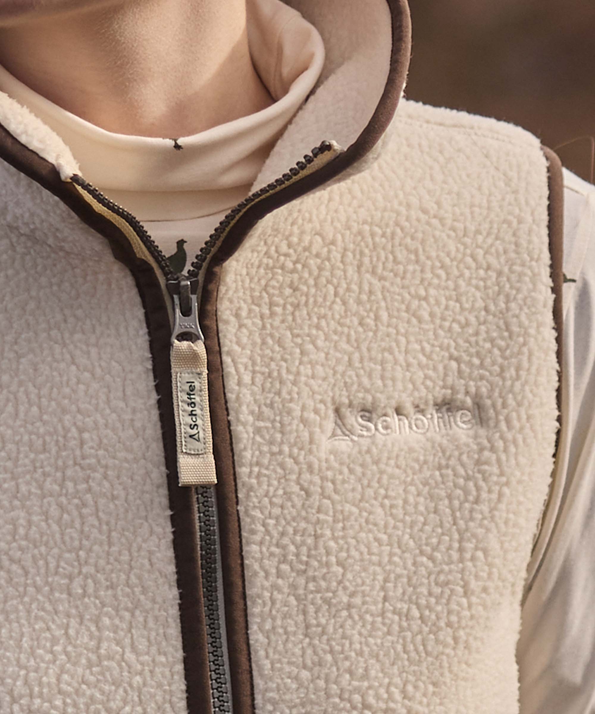 Close-up of a cream Schöffel sherpa fleece gilet collar showing the corduroy trim and pheasant-detail zip pull.