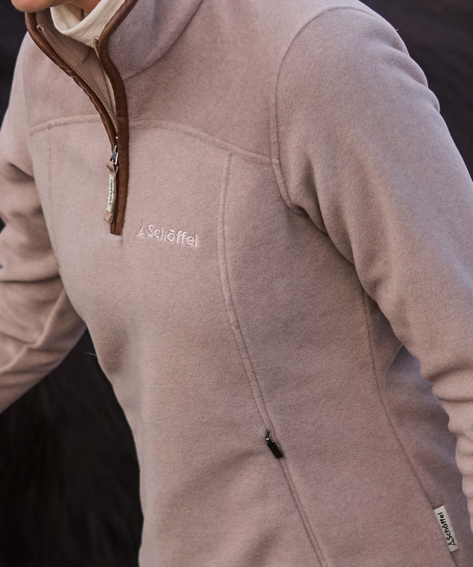Close-up of a taupe Schöffel fleece quarter-zip showing the shoulder pocket and zip detail.