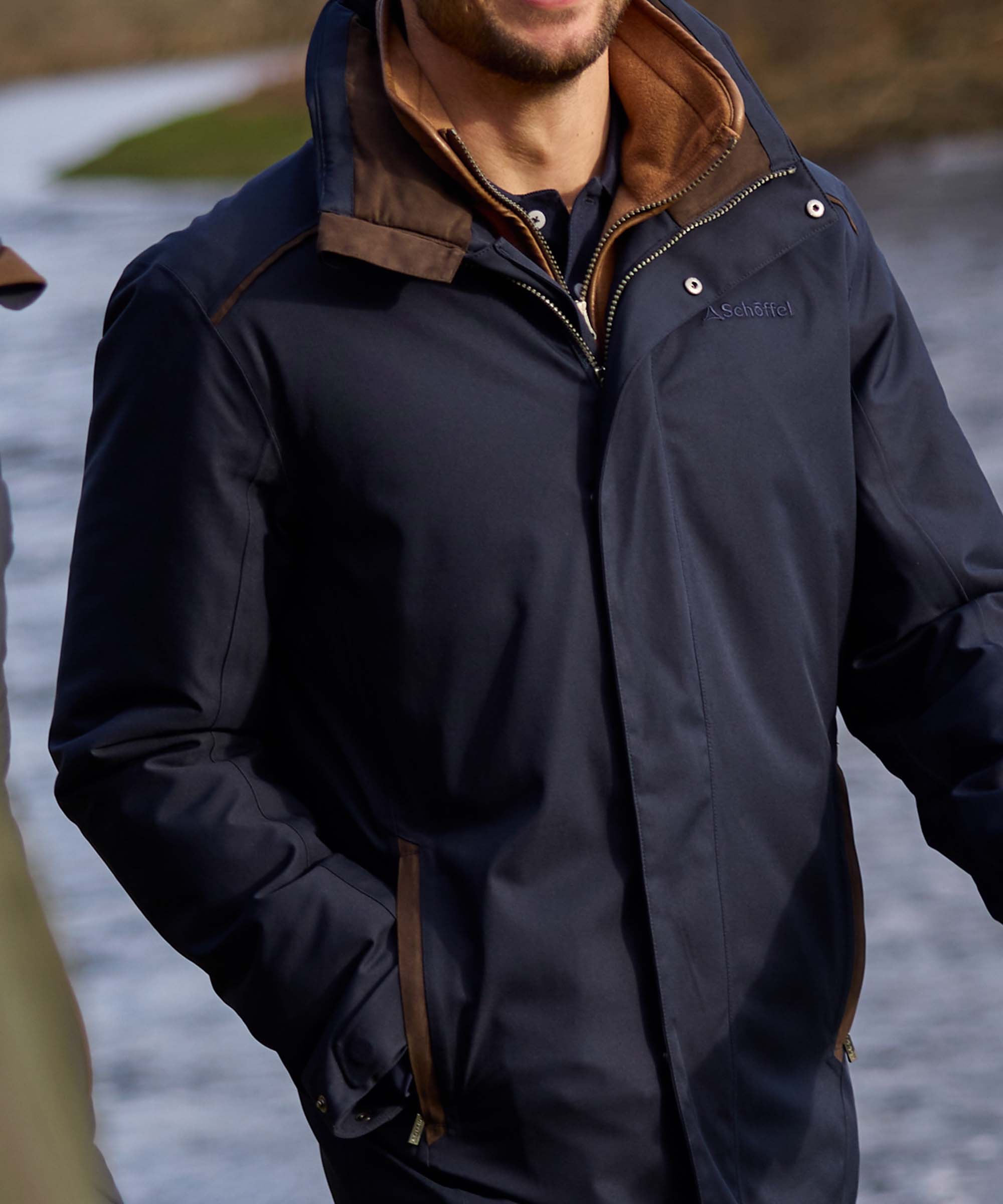 Close-up of navy waterproof jacket collar with brown suede and tan fleece detailing, Schöffel branding visible