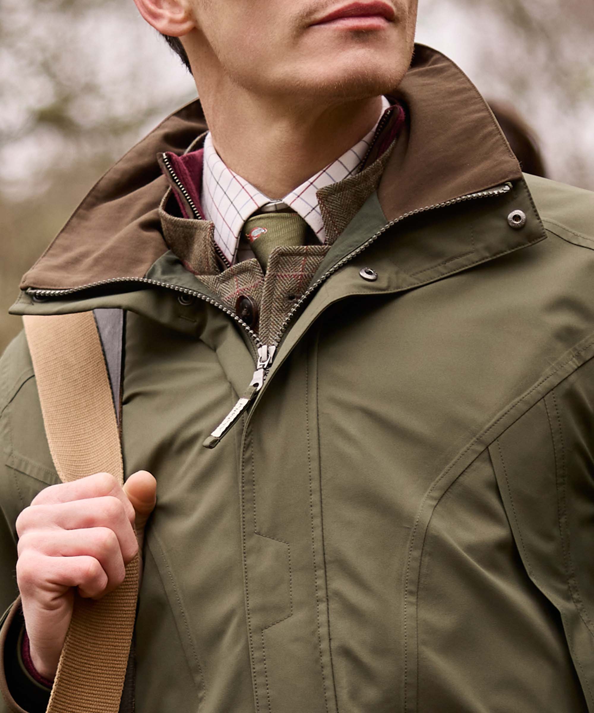 Close-up of an olive green Schöffel jacket collar with brown corduroy trim, worn with a tweed waistcoat, checked shirt and tie for a smart country look.