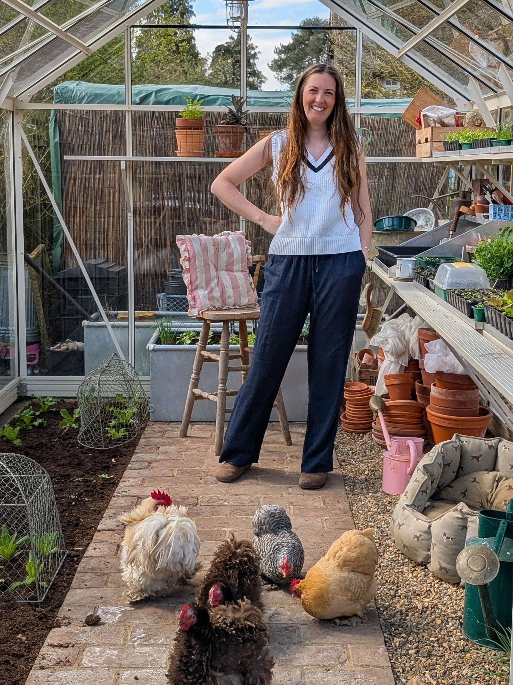 Woman standing in a greenhouse with chickens around her