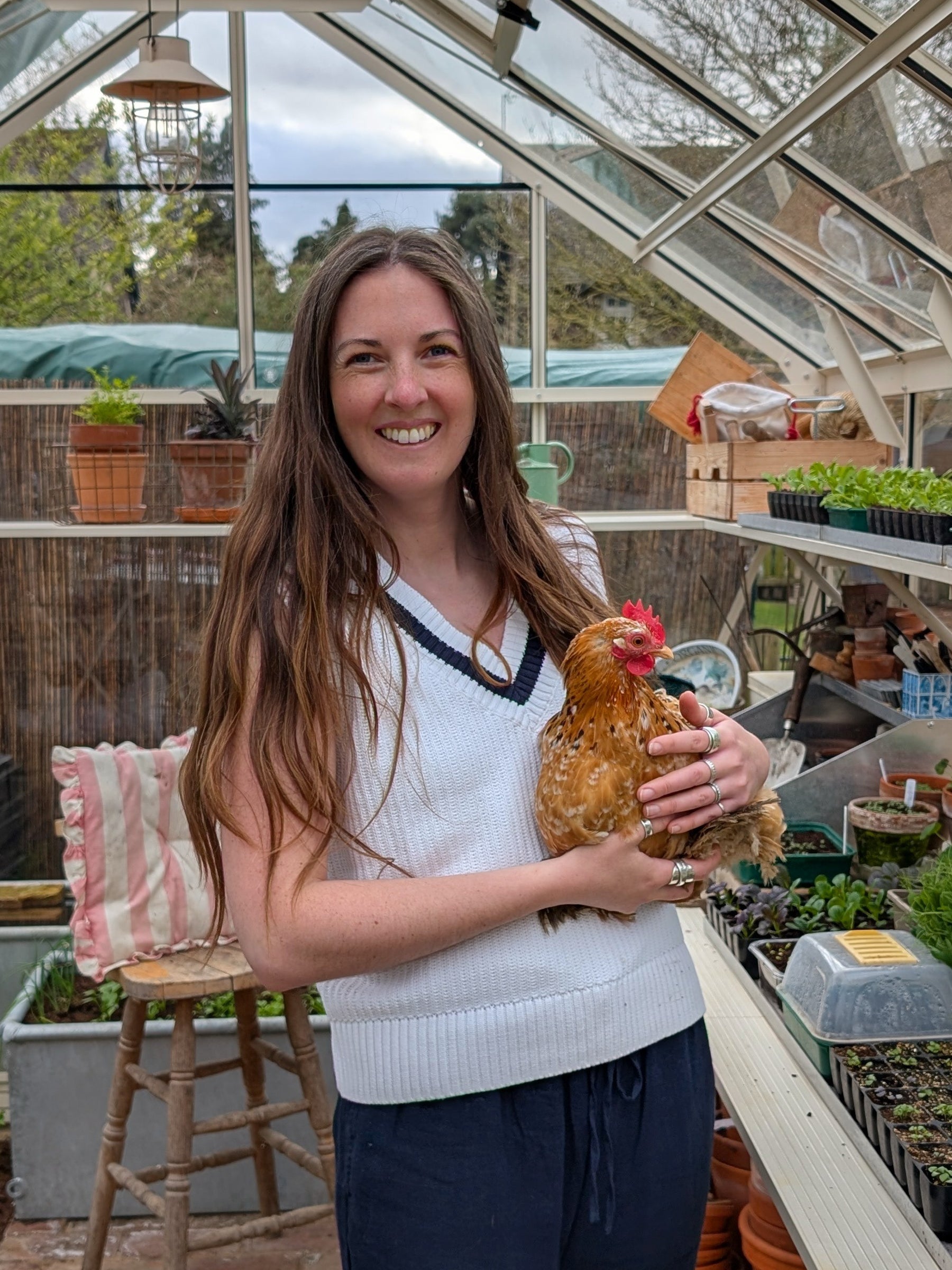 Woman holding a chicken in a greenhouse setting