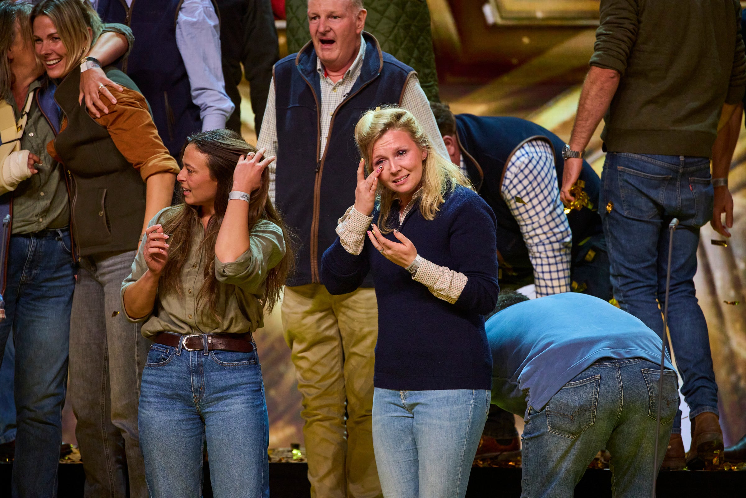 Group of people in a crowded area, some taking photos or videos.