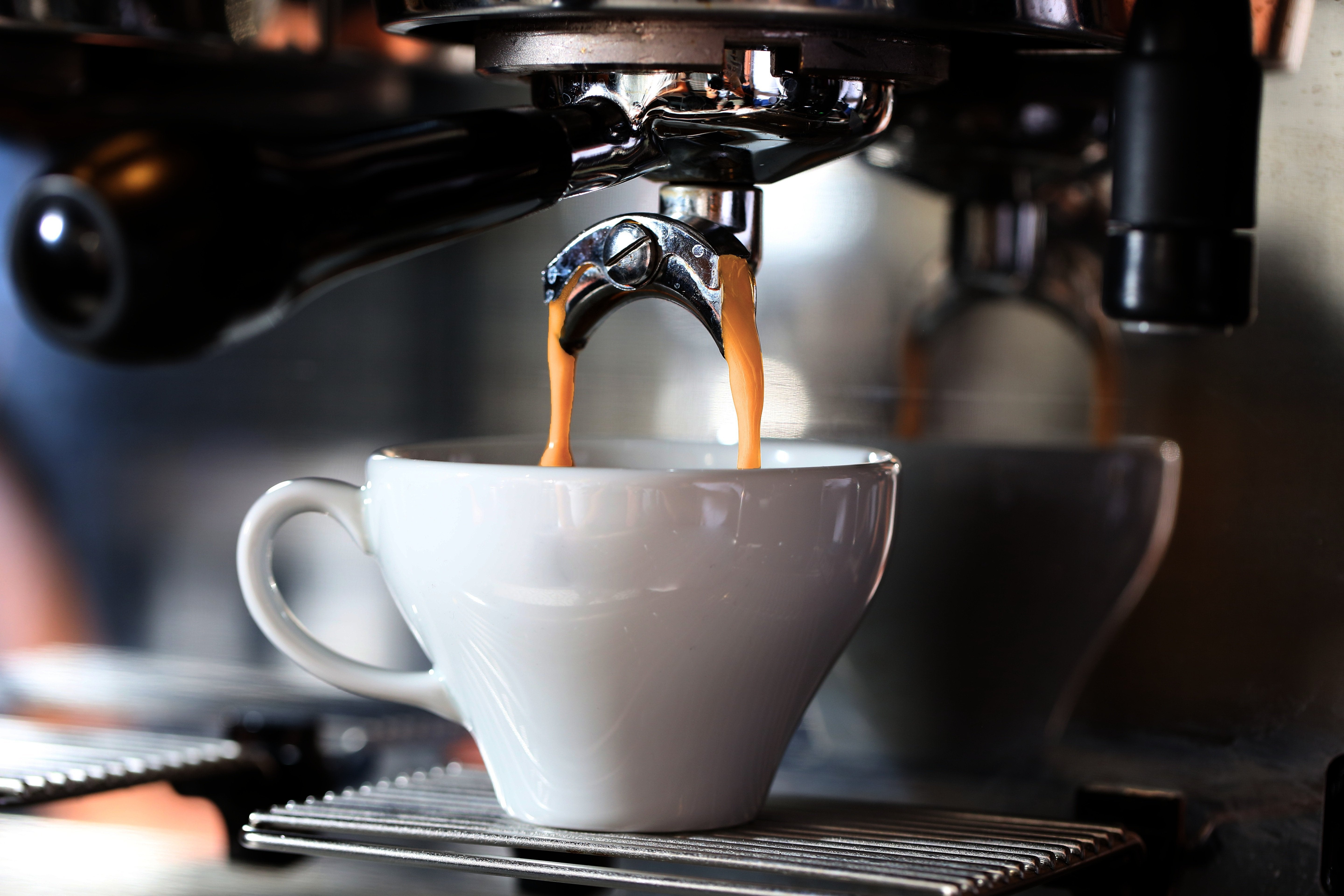 Espresso being poured into a white cup from an espresso machine.