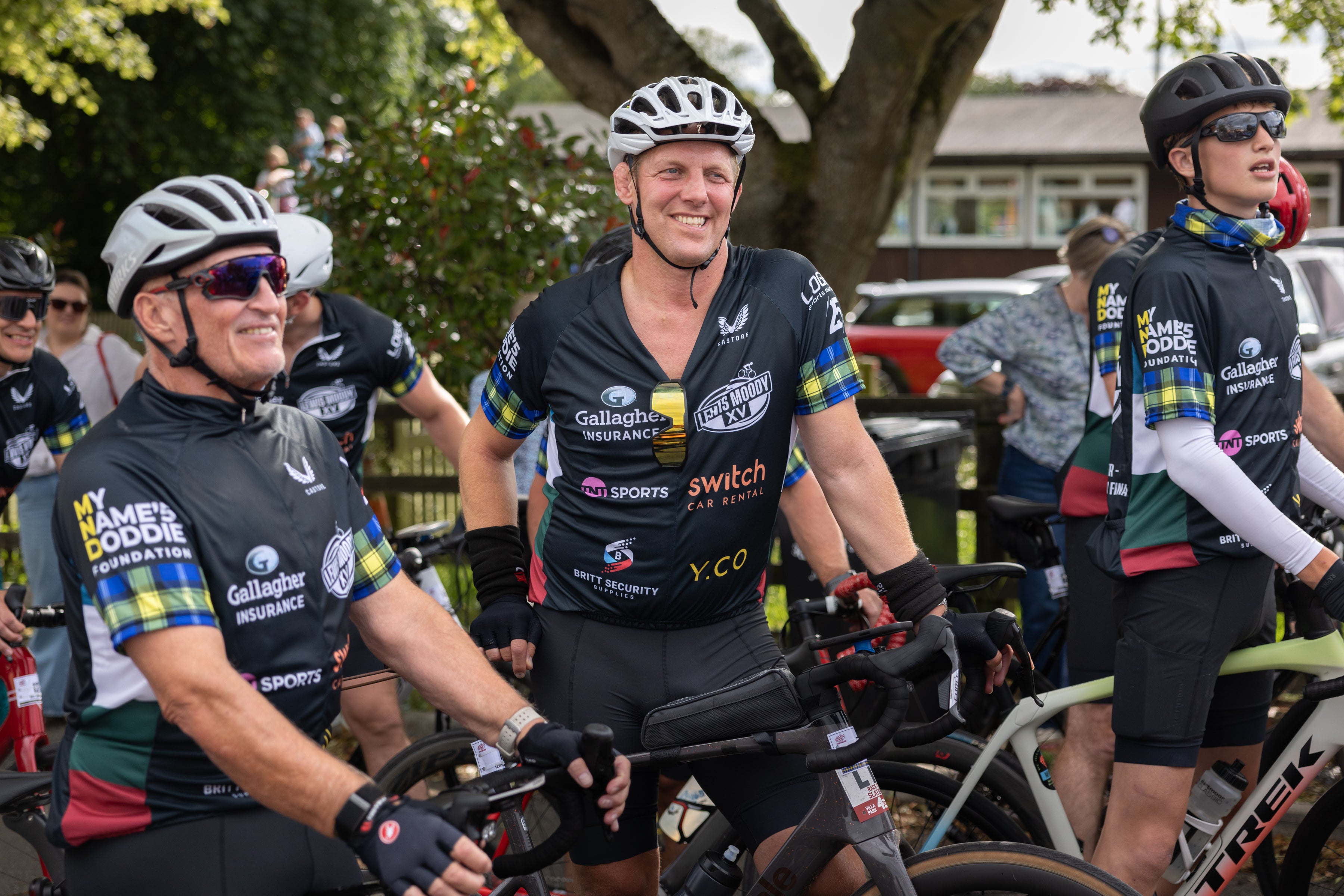 Group of cyclists in matching jerseys preparing for a ride outdoors.