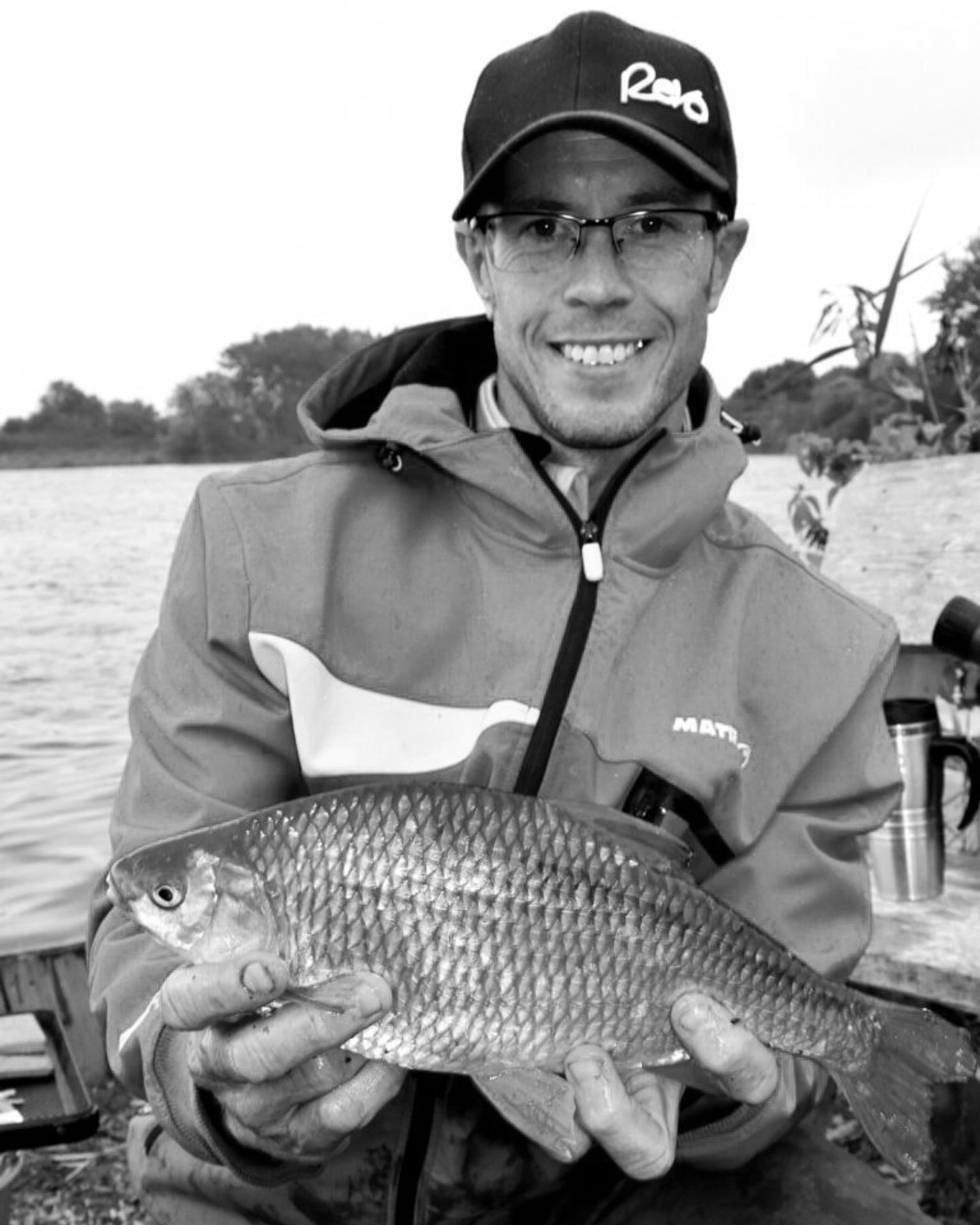 Paul Coulson holding a fish on a lake with a cap and jacket
