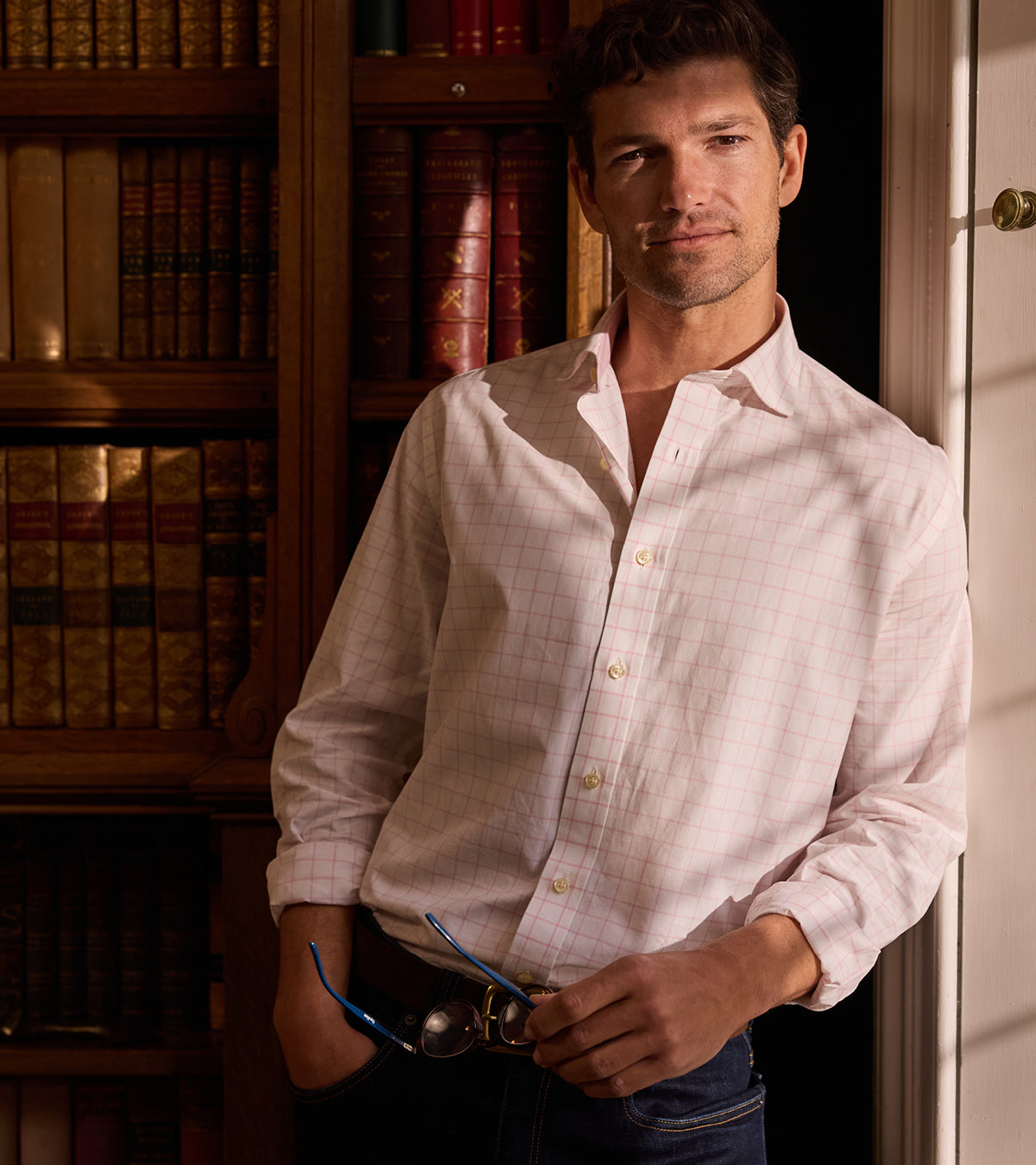 Man wearing a light-coloured shirt standing in front of a bookshelf