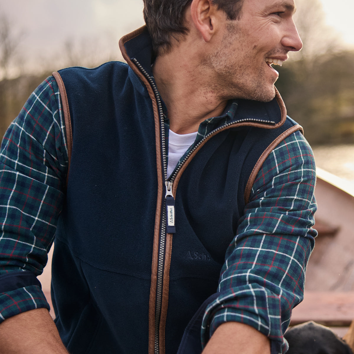 Man wearing a navy gilet with a checked shirt outdoors