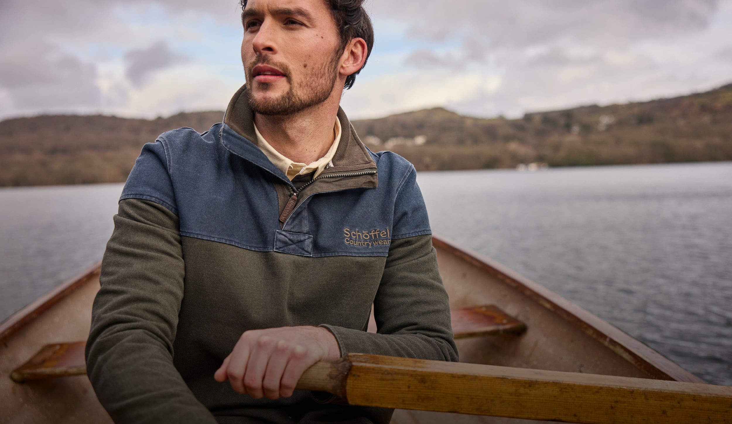 Man rowing a boat on a lake with mountains in the background