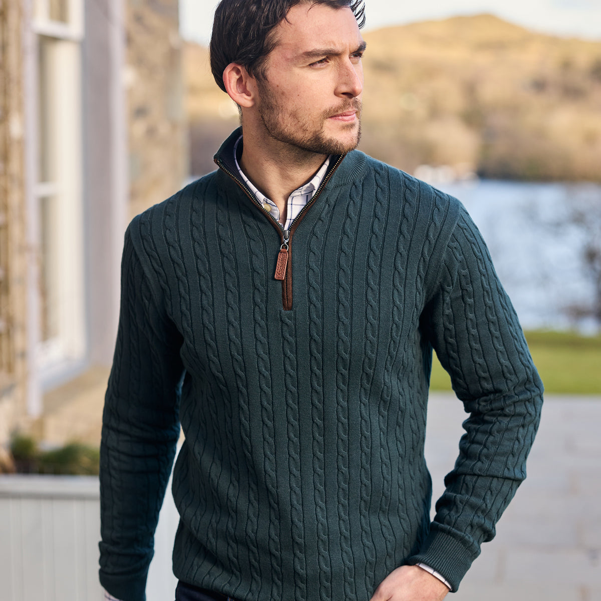 Man wearing a green cable knit jumper with a blurred natural background